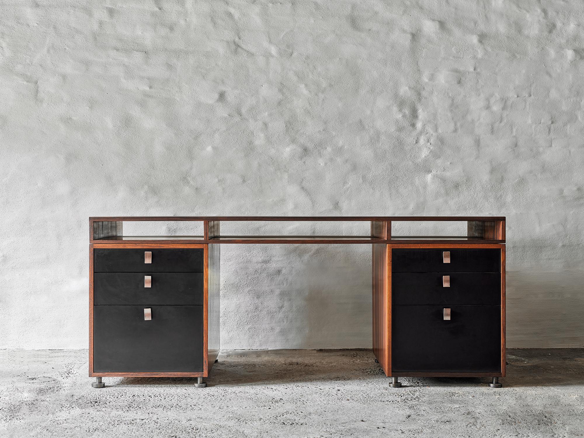 This refined and poised desk-table, designed by Belgian architect and furniture designer Jules Wabbes, is crafted from solid padauk wood slats and rests on adjustable disc-shaped feet. It features black veneer drawers with gun-barrel steel handles,