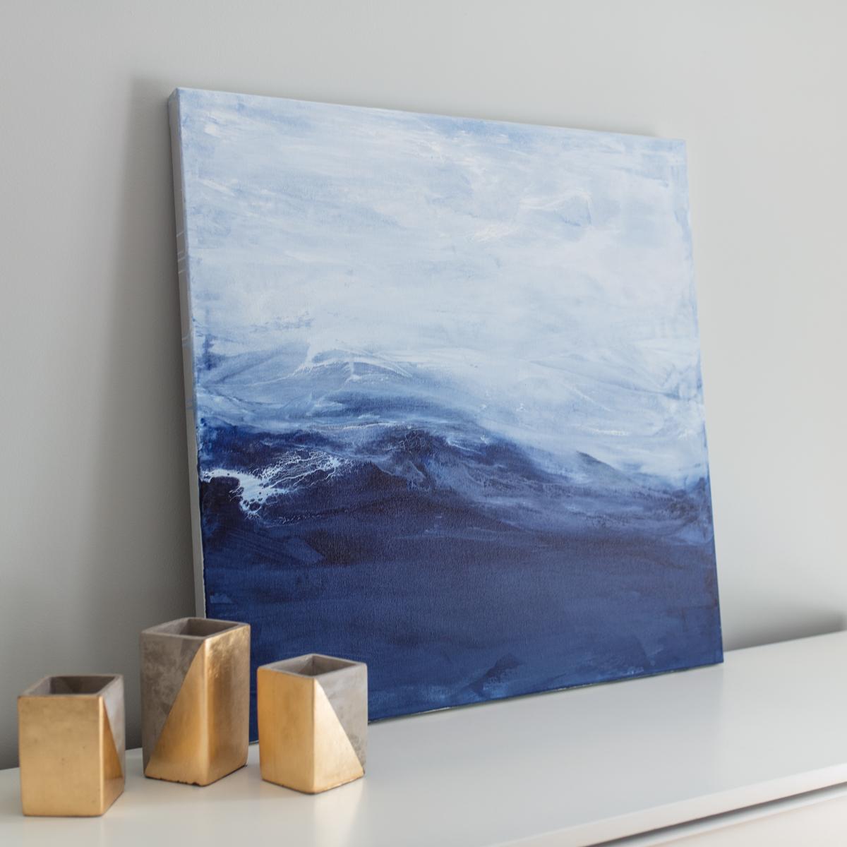 This moderately sized coastal abstract painting is made with acrylic paint on canvas, gallery wrapped with silver painted edges. Awash in a sea of blue, the softest touch of white dances across this fresh horizon, giving a beautifully coastal design