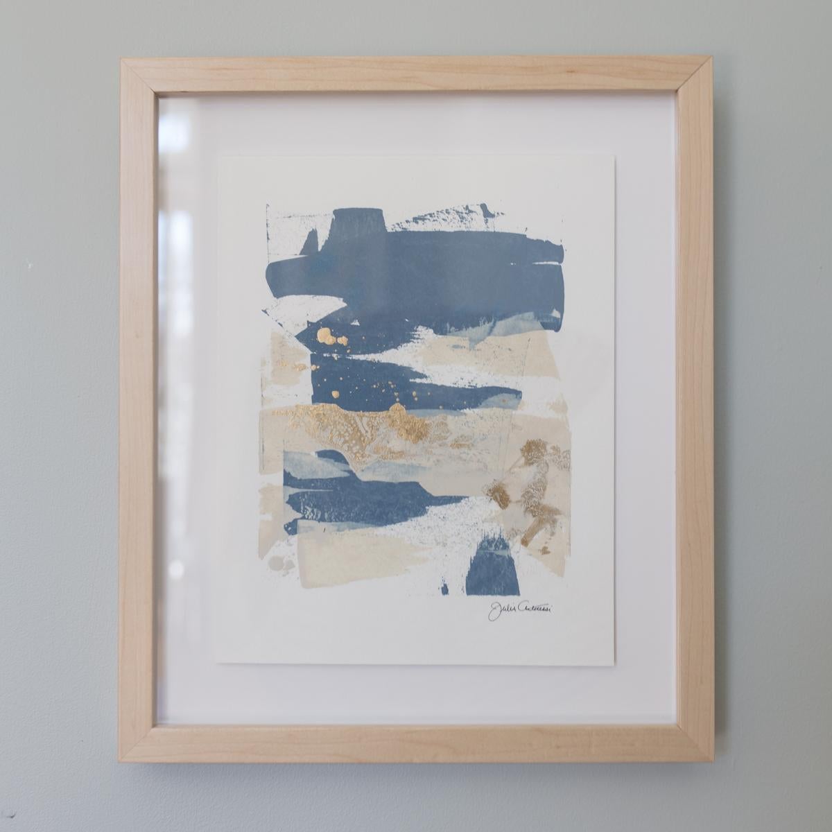 This original abstract painting is made on paper, and composed of blue, and creme strokes of paint with metallic gold accents. It is float mounted and framed in a solid natural wood moulding. Framed, it measures 13.25" x 15.75".  It is wired and