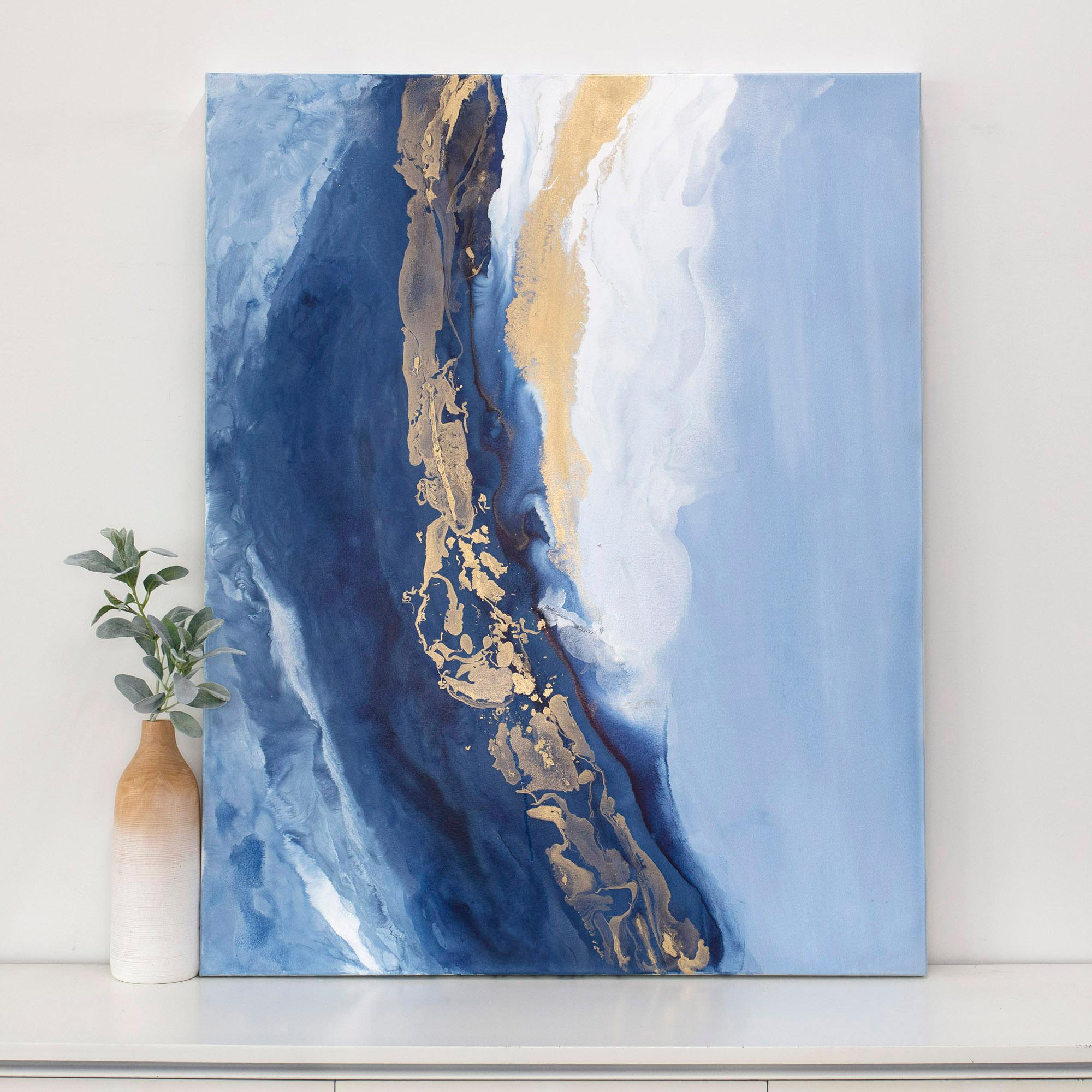 Este cuadro abstracto contemporáneo de Julia Contacessi presenta capas de tonos azules claros y aguados en el centro del lienzo, con capas más claras y texturadas a ambos lados. Encima de la zona azul central, la artista ha añadido un acento dorado