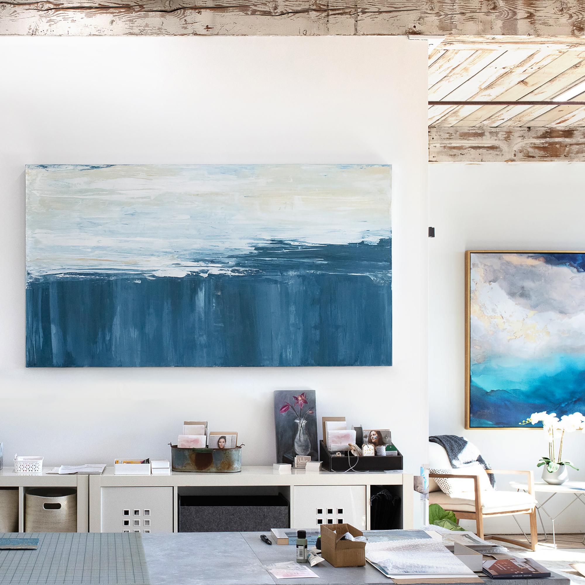Questo grande quadro astratto di Julia Contacessi presenta una tavolozza fredda con un blu intenso nella metà inferiore della composizione e un bianco e toni neutri stratificati in pennellate nella metà superiore dell'opera. Questo quadro astratto è