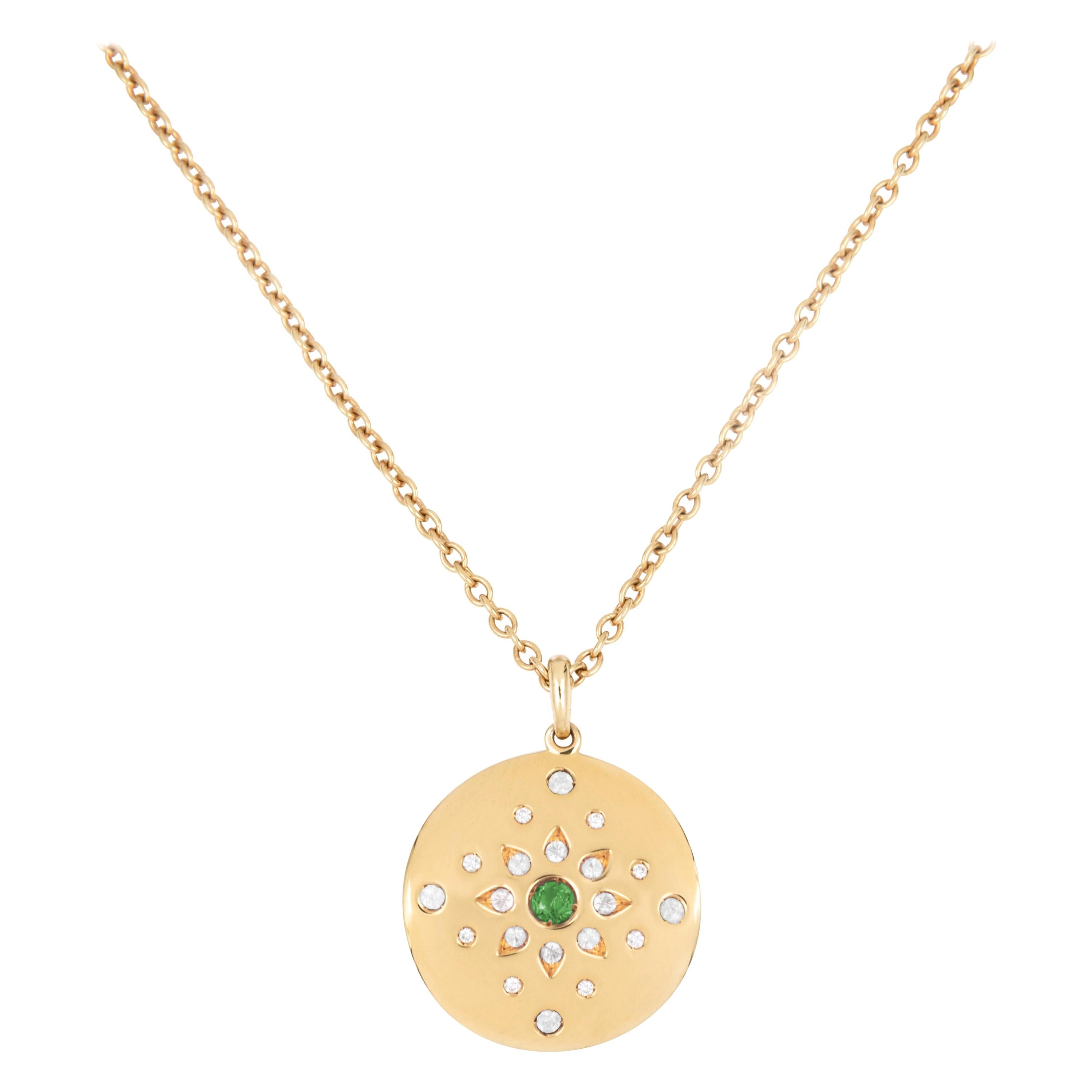 Set composed of an 18 karat yellow gold pair of earrings and of a necklace with a round disc pendant and an adjustable long chain. The pendant and each of the earrings are individually set with 21 gemstones including a central emerald and diamonds.