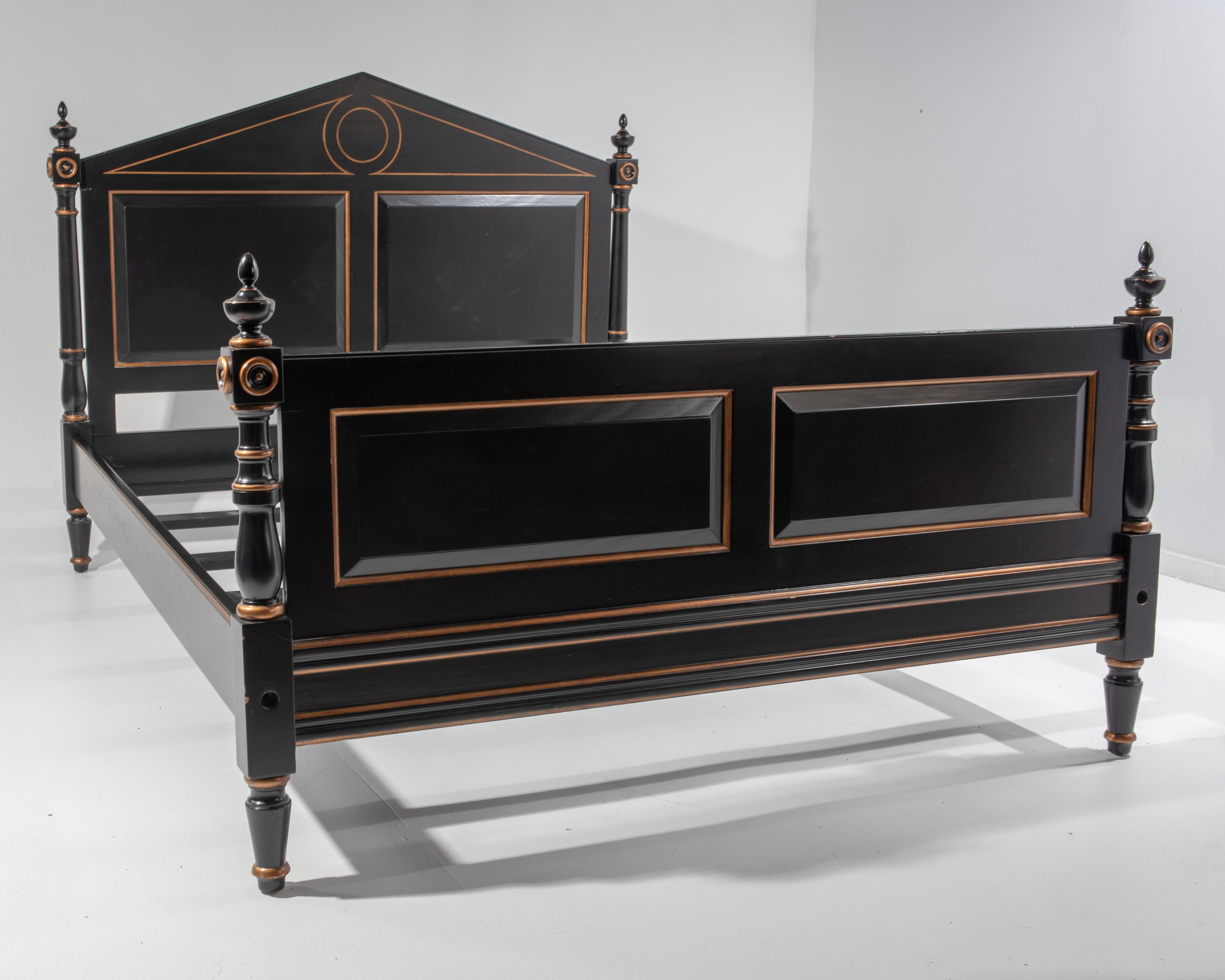 Stately and impressive black and gold Hollywood Regency style bed having neoclassical triangular headboard frieze and wonderful decorative finials. Queen size. H of the footboard (finials) 37