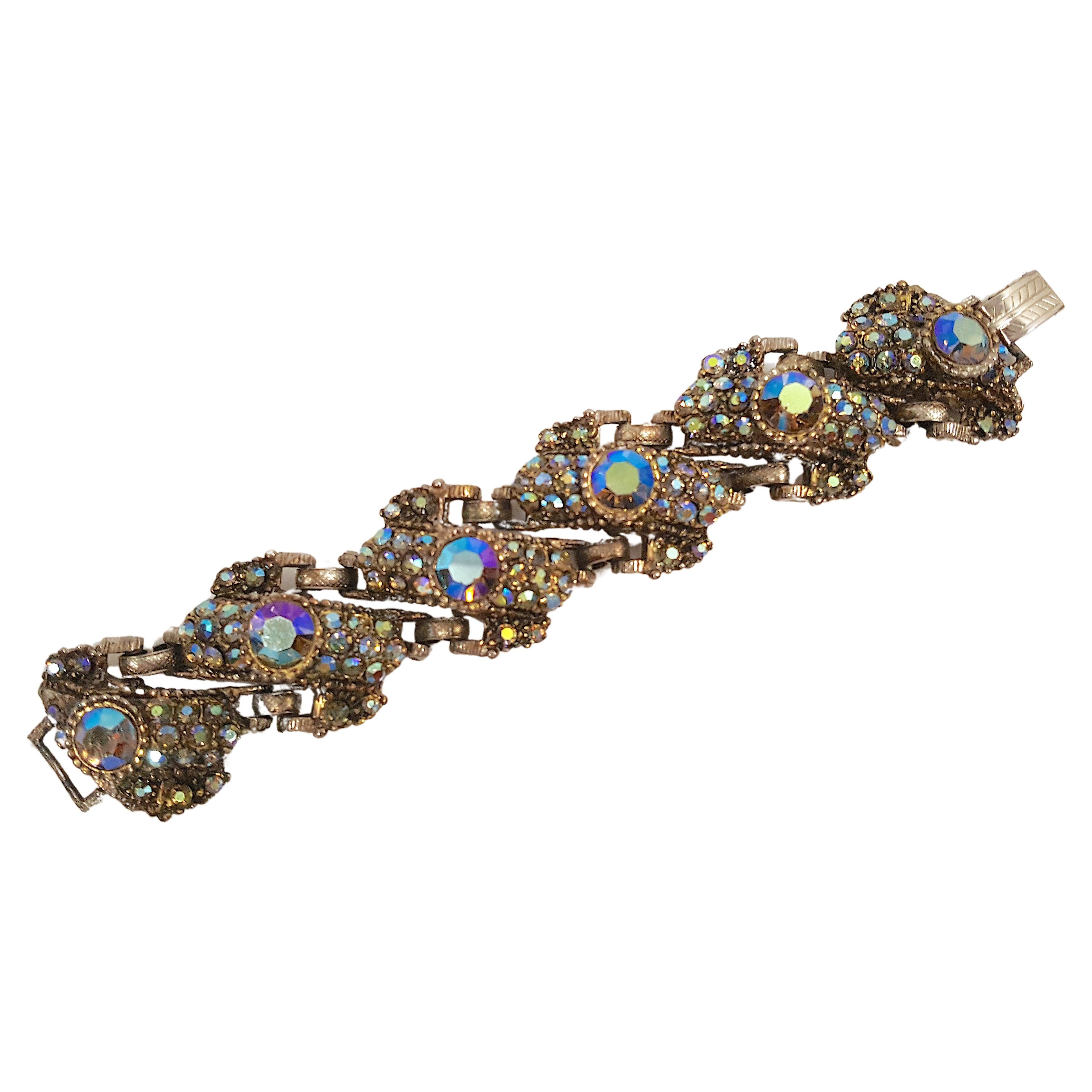 Les designers Delizza &New de New York ont créé à la fin du milieu du siècle dernier ce bracelet en bronze à six maillons, lourd et coloré, qui attire l'attention. Il est incrusté de cristaux aurores boréales (AB) de deux tailles, tous sertis dans