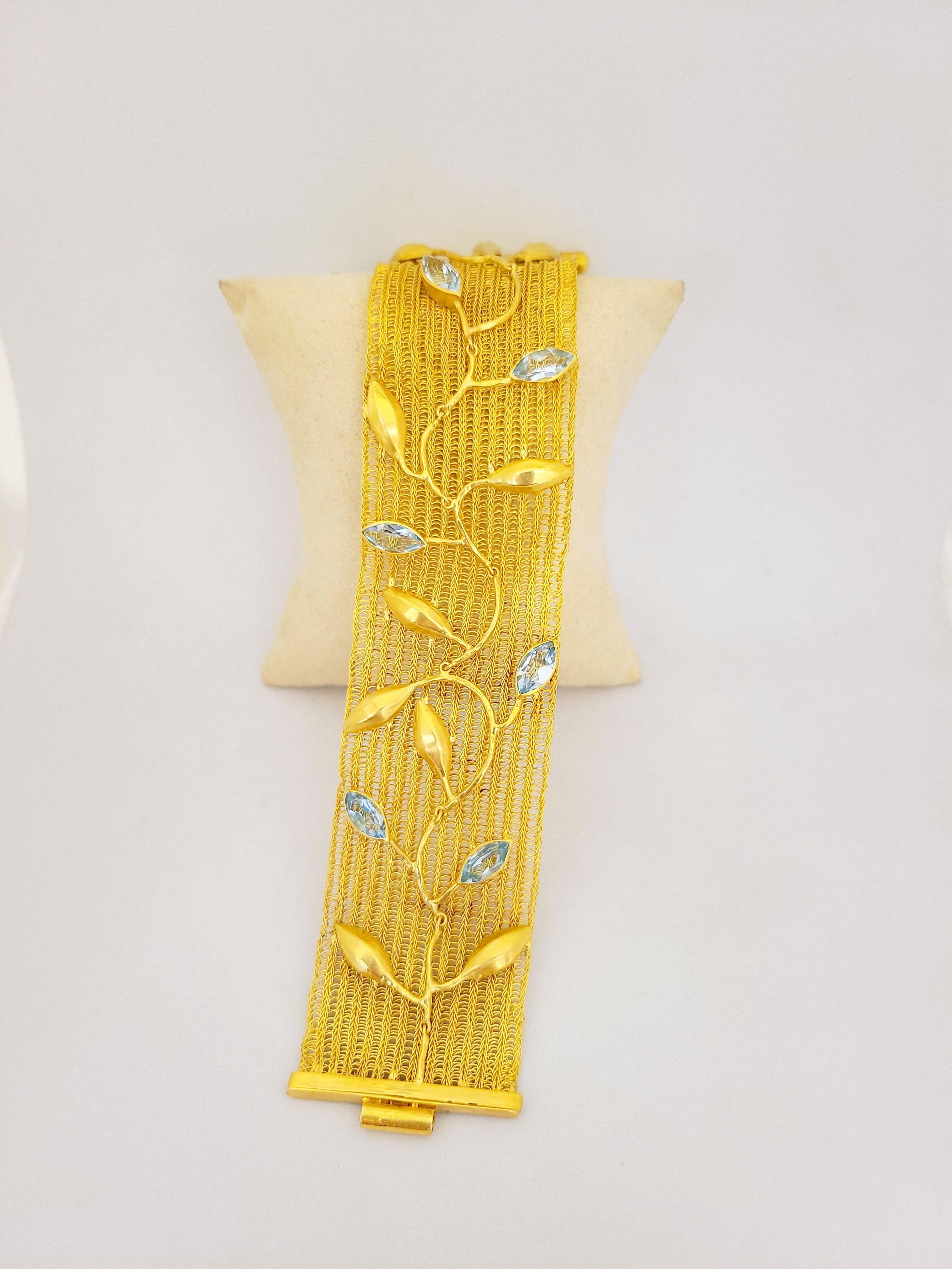 This Beautiful bracelet is composed of hand-woven 18Kt yellow gold and accented with 7 Carats of marquis cut blue topaz, and satin finished gold leaves. The piece is timeless and feminine. 
Bracelet measures 7