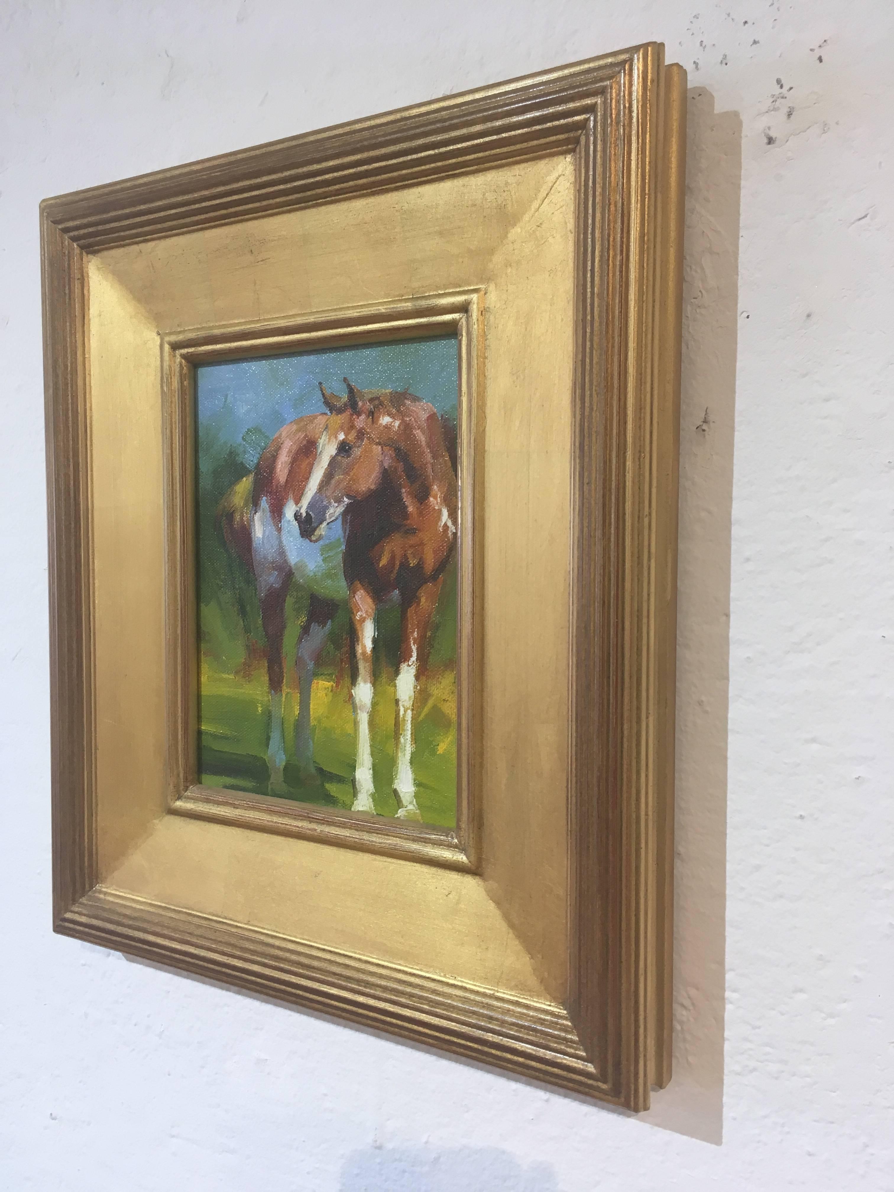 This is an oil painting single paint pony standing with its head lowered. It's body is positioned at a three-quarter view. The white and tan horse standing in dappled sunlight in a grassy field with implied trees and a blue sky. To view more images,