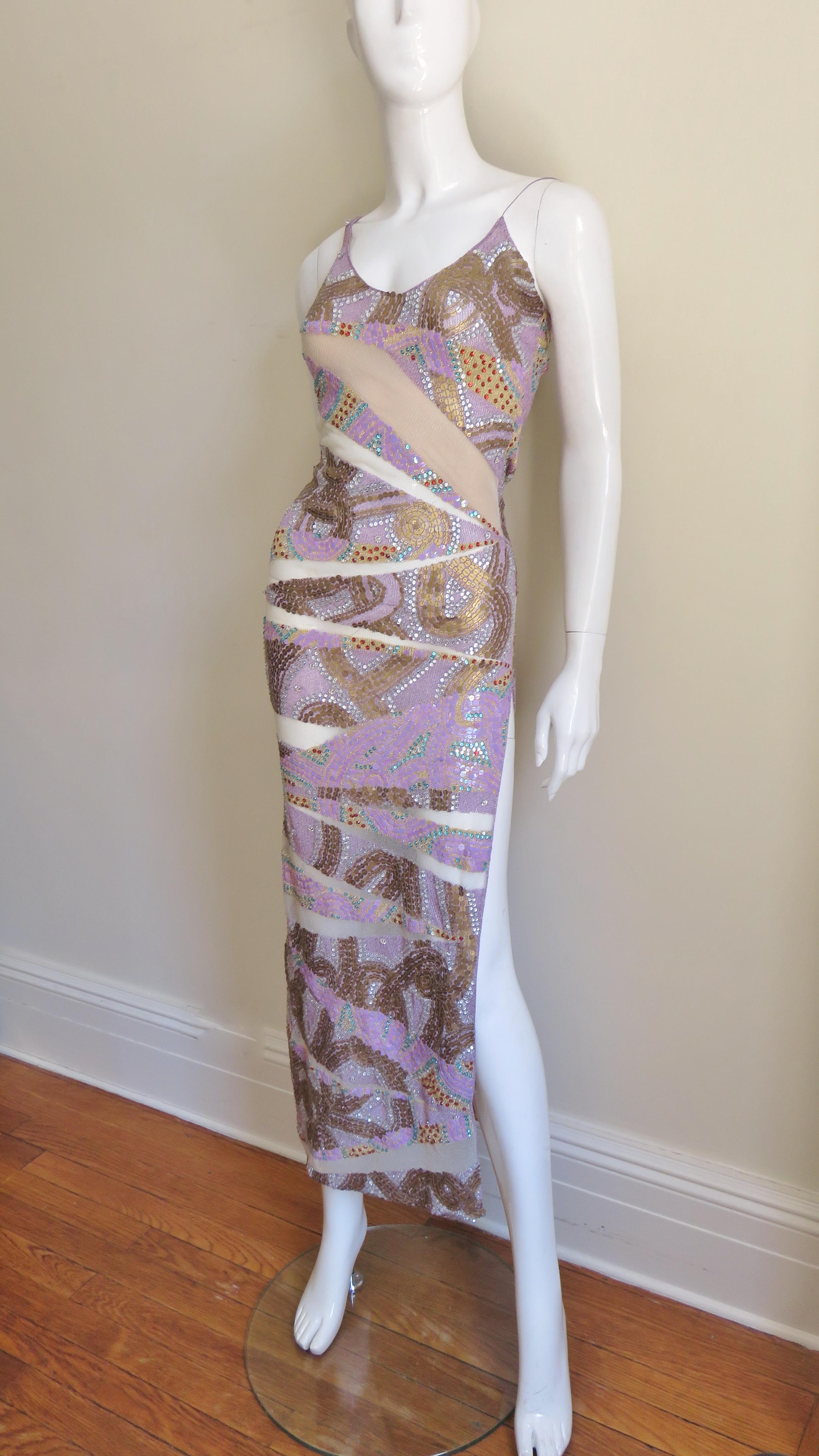 A beautiful bodycon dress from Julien MacDonald.  It is fitted through the hips then flares slightly to the hem which has a side slit.  The bodice has a spaghetti strap and a larger strap. The dress has alternating wedges of lilac and gold sequins