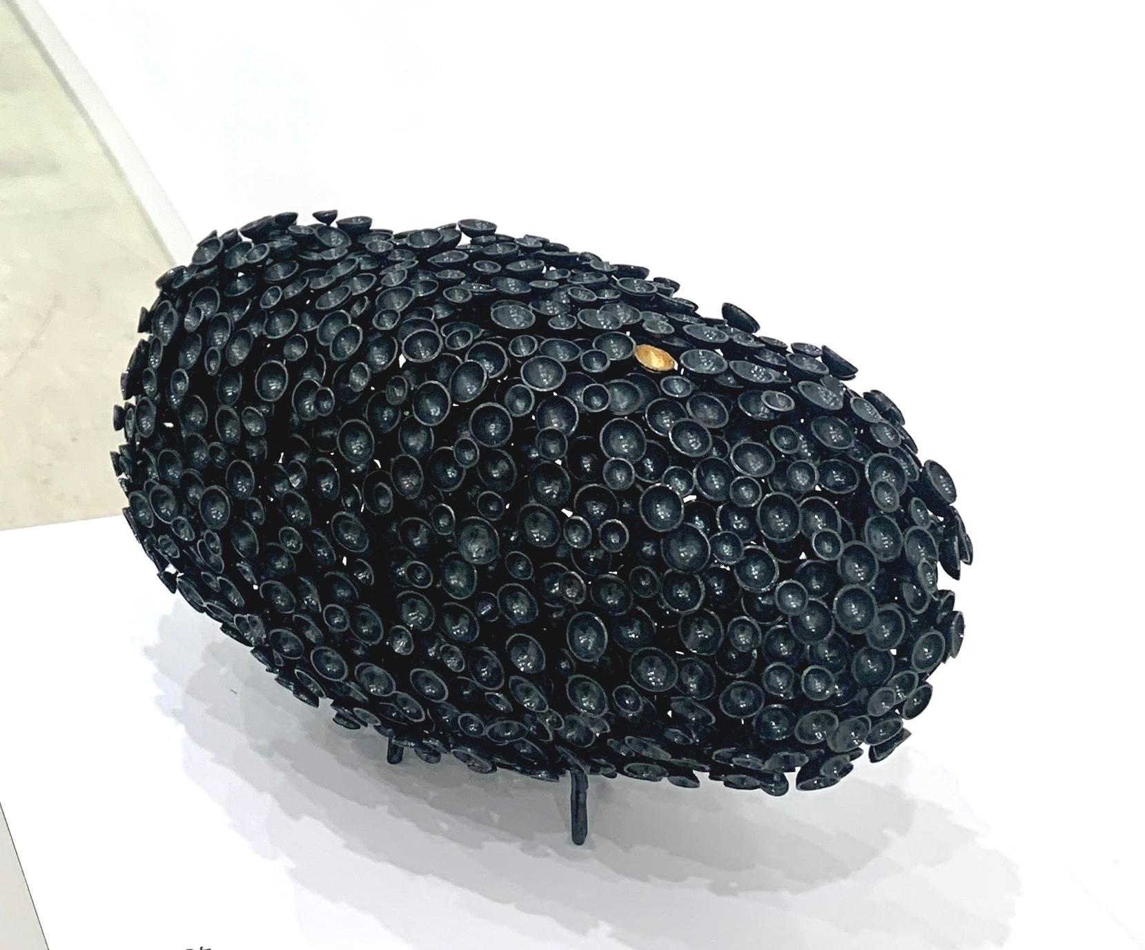En esta escultura metálica 3d exquisitamente soldada, Juliette Frescaline resalta la individualidad con un círculo dorado en medio de un mar de grises. La escultura se titula acertadamente 