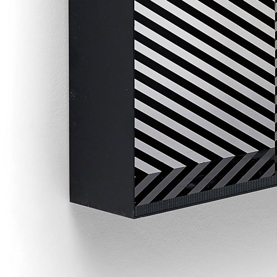 Relief 13
Aluminium box multiple with screenprint in black and white, with the original perspex lid.
'Relief 13' is an abstract, three dimensional, op art sculpture made from metal and perspex. The back of the piece shows black and white diagonal