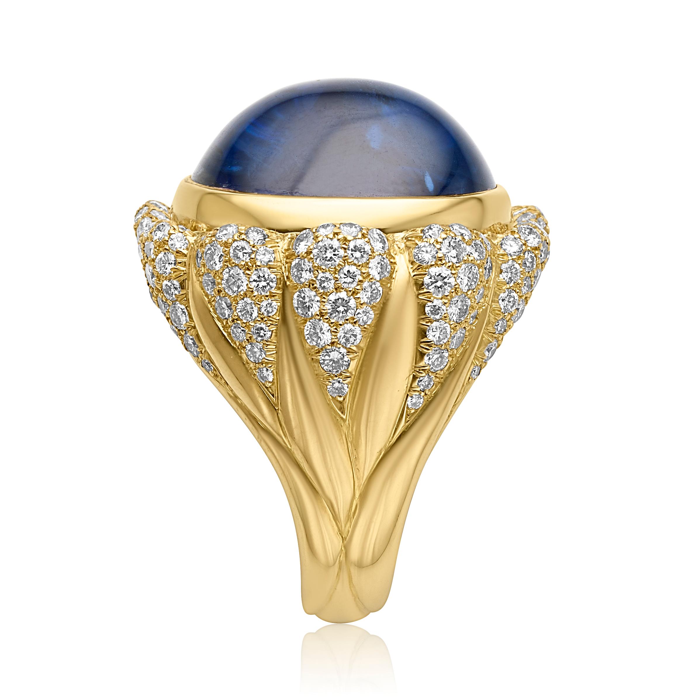 From designer Julius Cohen, circa 1980s, 18 karat yellow gold blue sapphire and diamond cocktail ring. This ring is crafted with a center 41.78 carat oval shape double cabochon cut no heat blue sapphire. Accenting the blue sapphire, 180 pave set