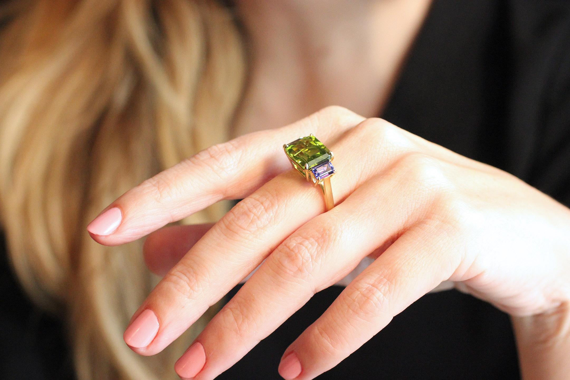 This 18 Kt Gold Ring features bright, clear gemstones with great color saturation and presence.  Containing one emerald-cut Burma Peridot (7.24 Cts.) and two emerald-cut Tanzanites (1.37 Cts.).  This ring is currently size 6 1/2, but can be sized if