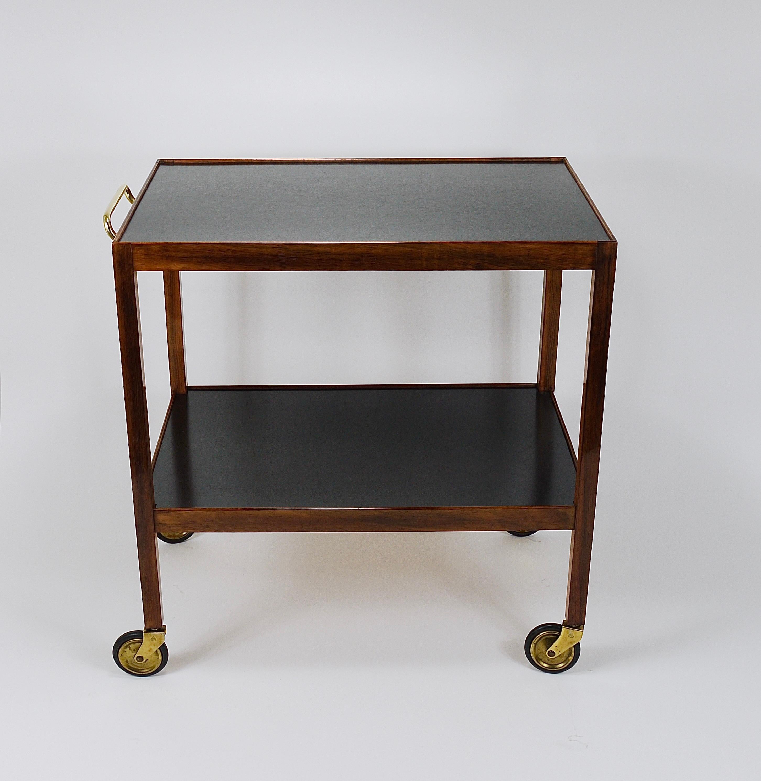 An elegant, sleek, and minimalist Austrian two-tiered bar cart / serving table from the 1930s. Designed by Julius Jirasek and executed by Werkstätte Karl Hagenauer Vienna, Austria. This piece showcases refined craftsmanship. It is made of solid