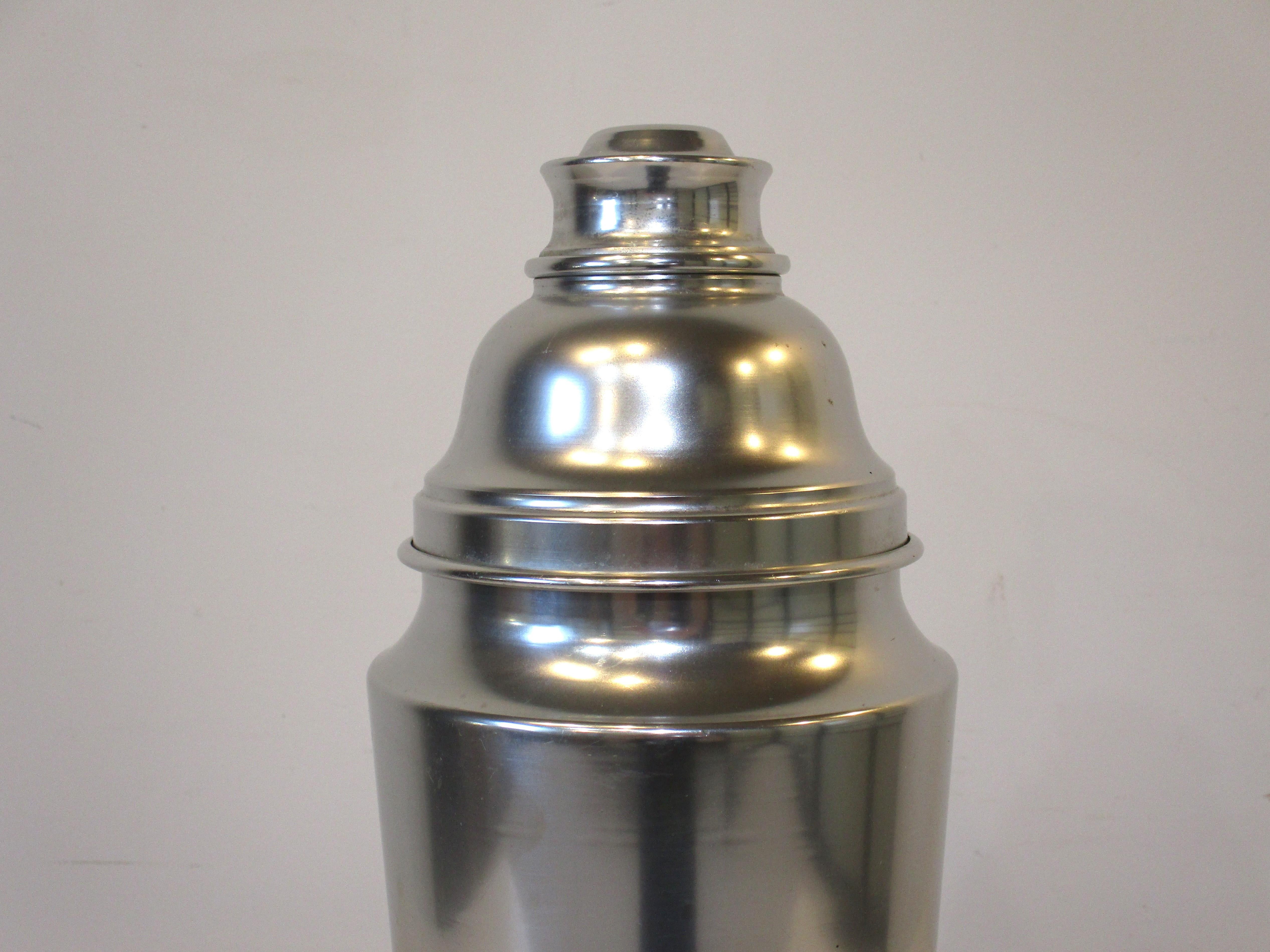 A very large jumbo sized cocktail shaker formed in aluminum with large top and built in strainer with cap. This is your summer party sized mixer shaker or called a hotel shaker that would be used in their bar to server a room full of customers.