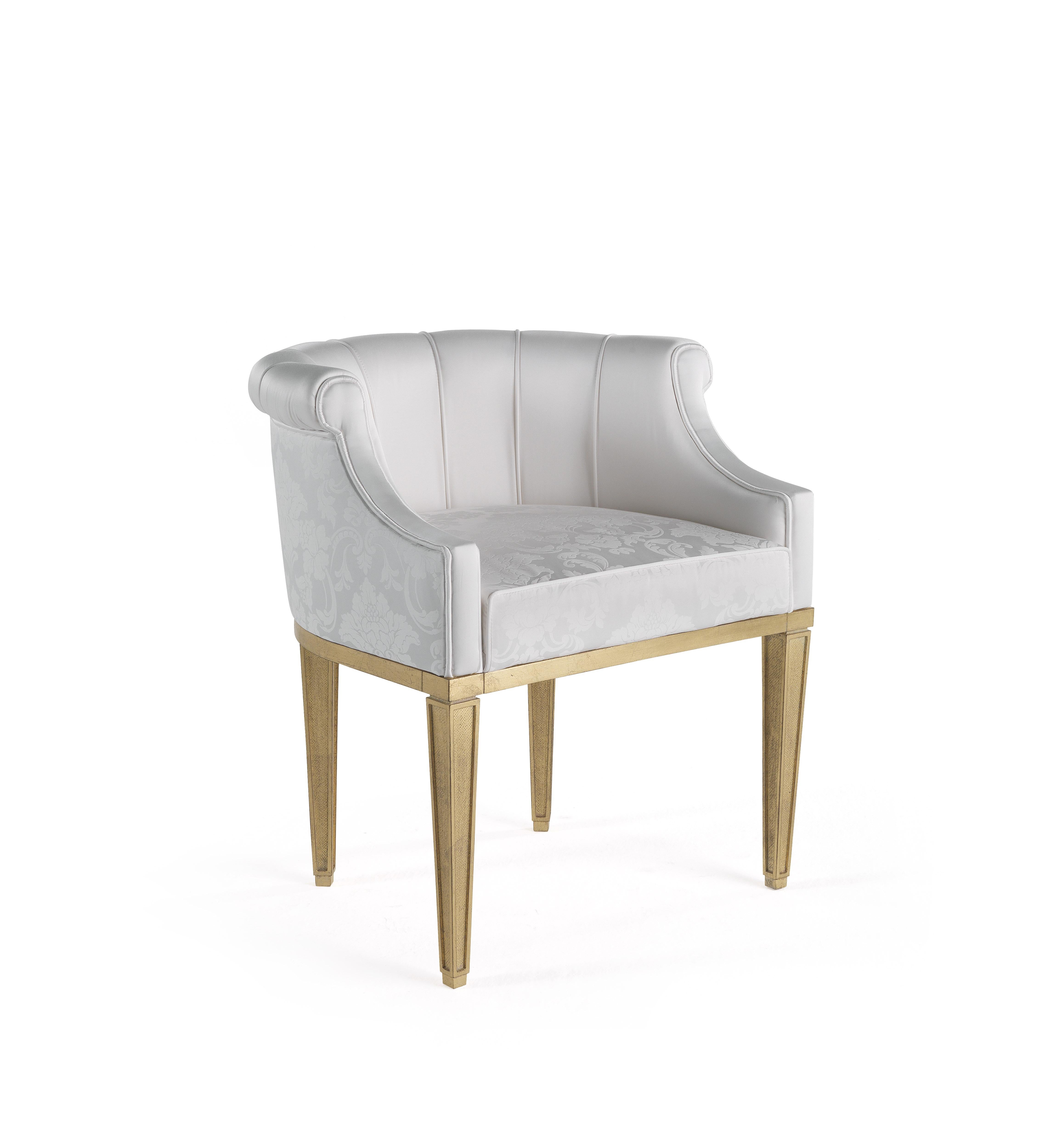A mi-chemin entre la chaise et le fauteuil, Fuji est un meuble raffiné qui exprime un style classique frais et lumineux. Elle présente un dossier en forme de coquillage recouvert de satin de soie de la collection et des pieds à la finition dorée