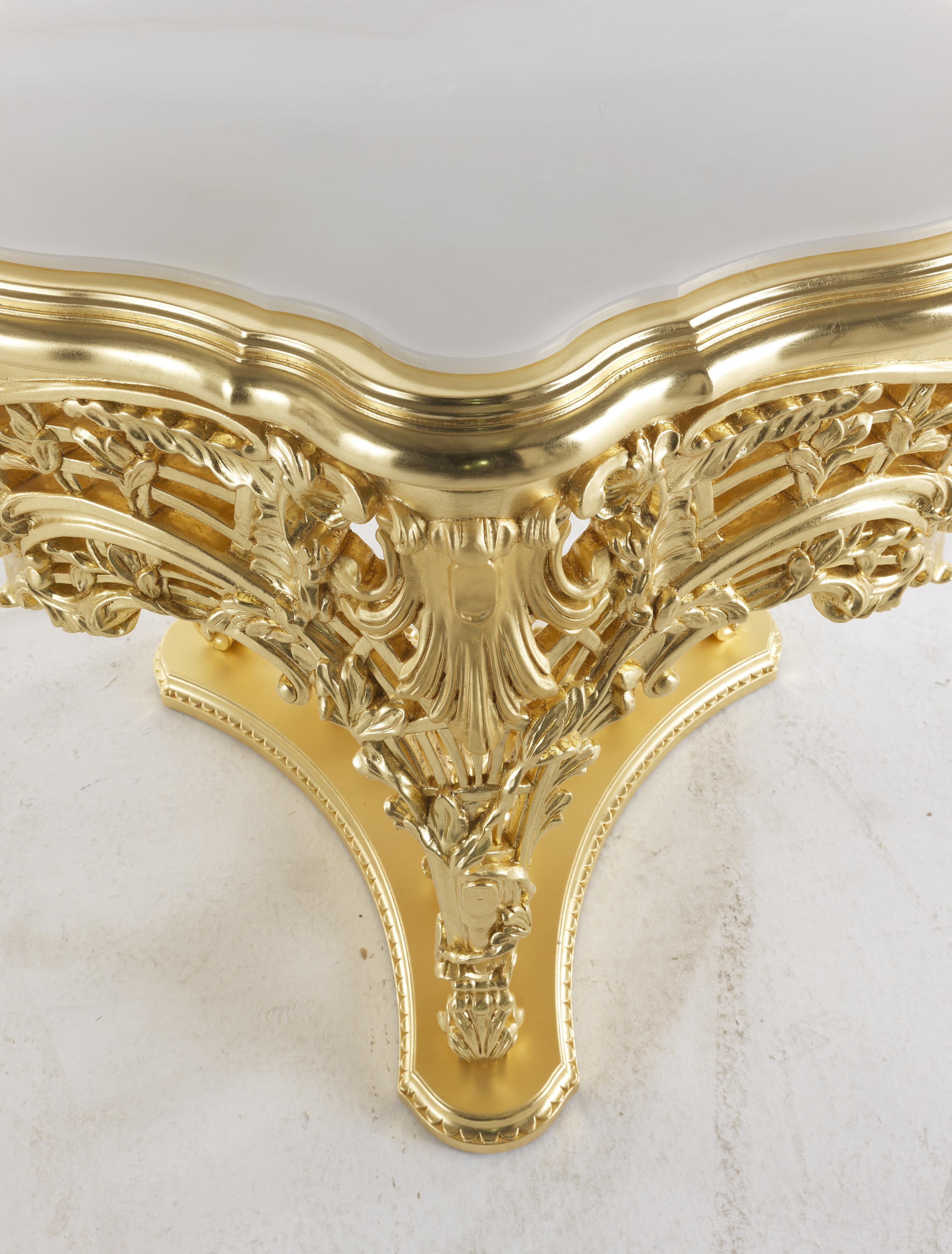 Helios is a refined side table in hand-carved beech wood with a glossy and matt gold finish. An exclusive and luxurious piece of furniture, which represents an example of Baroque cabinet-making of great refinement. The carvings of the very rich base