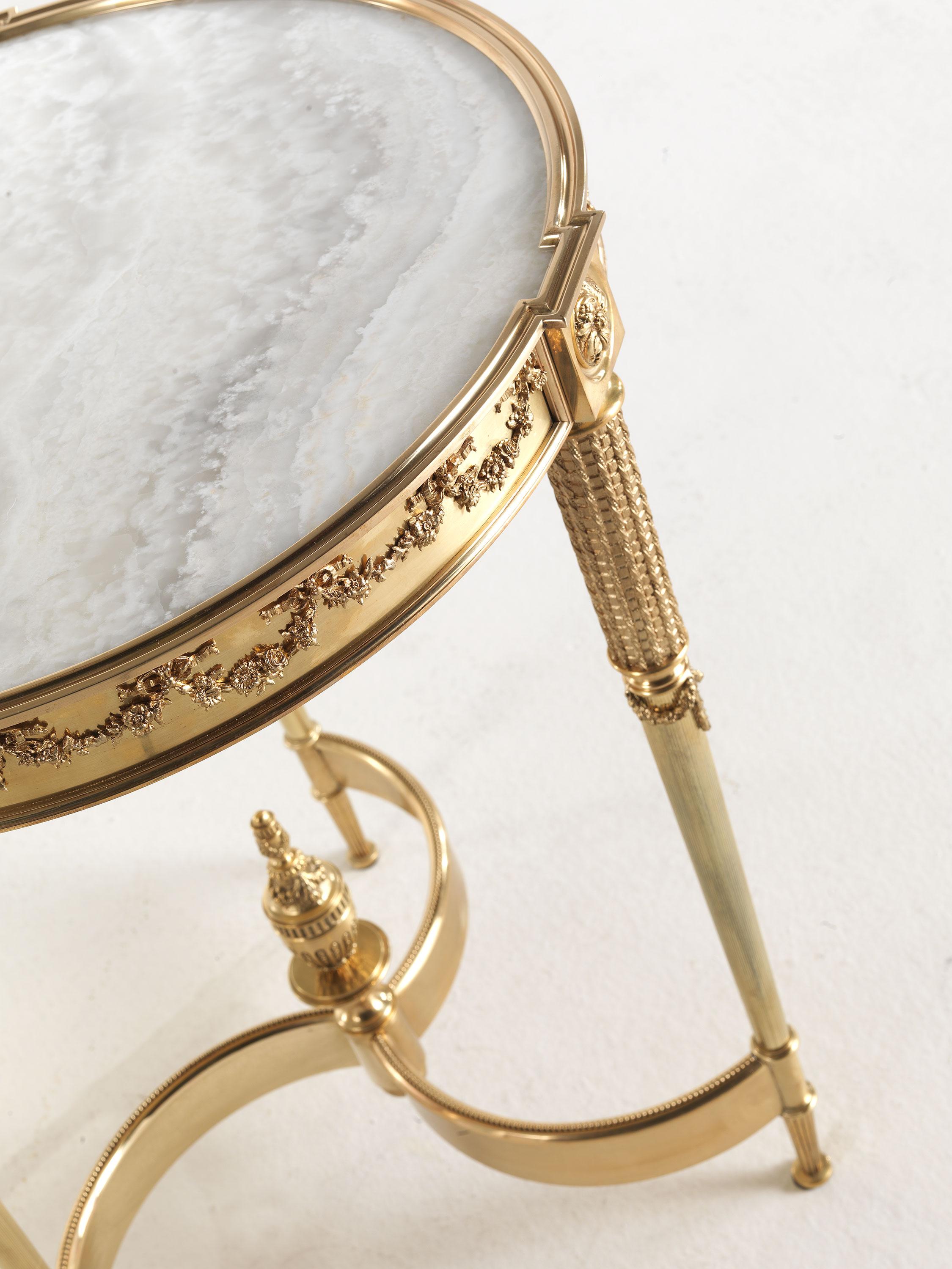 Pleasure is a line of furnishings characterized by an elegant and refined charm. This side table features brass legs with an antique finish and a cross that ends with a central decorative element, while the precious marble top completes the whole