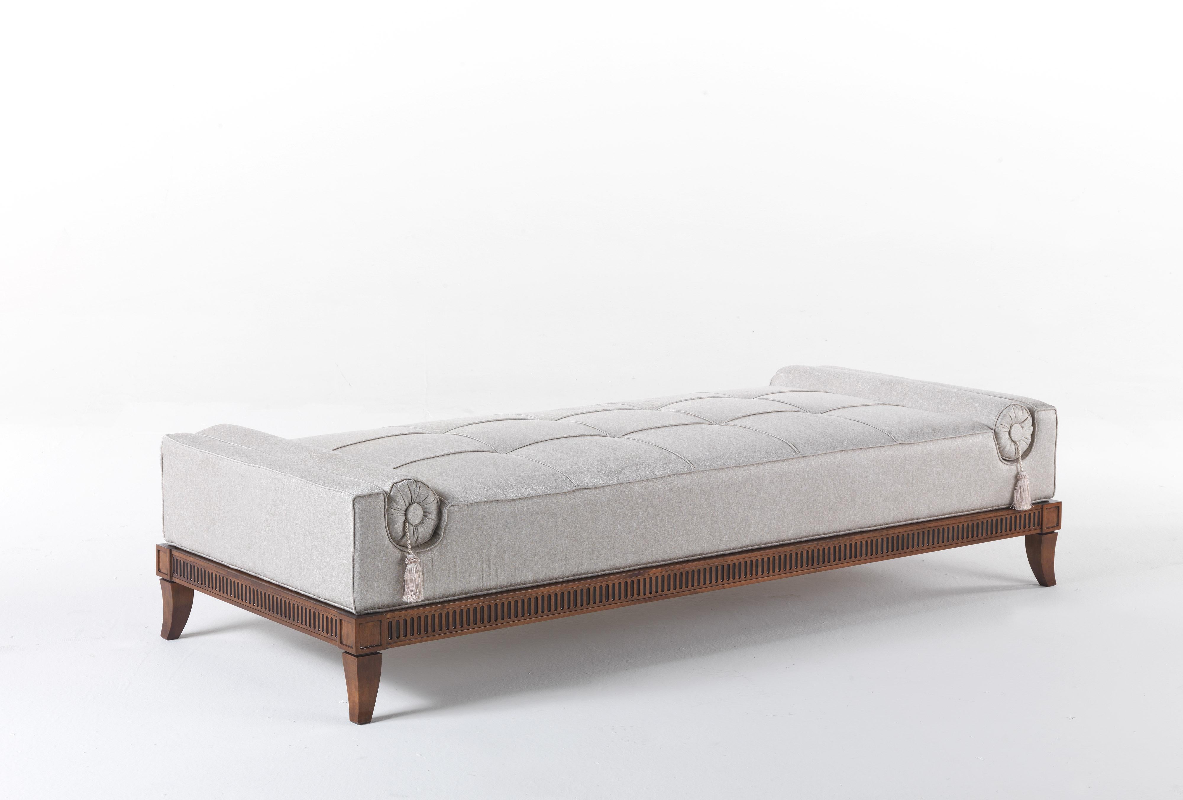 A bench with a rigorous, sophisticated line, made gentle by the softness of the covering and the precios detail of the roll cushions with silk tassels. 
Psyche Bench with structure in beechwood finished in walnut J284N. Padding in foam. Upholstery