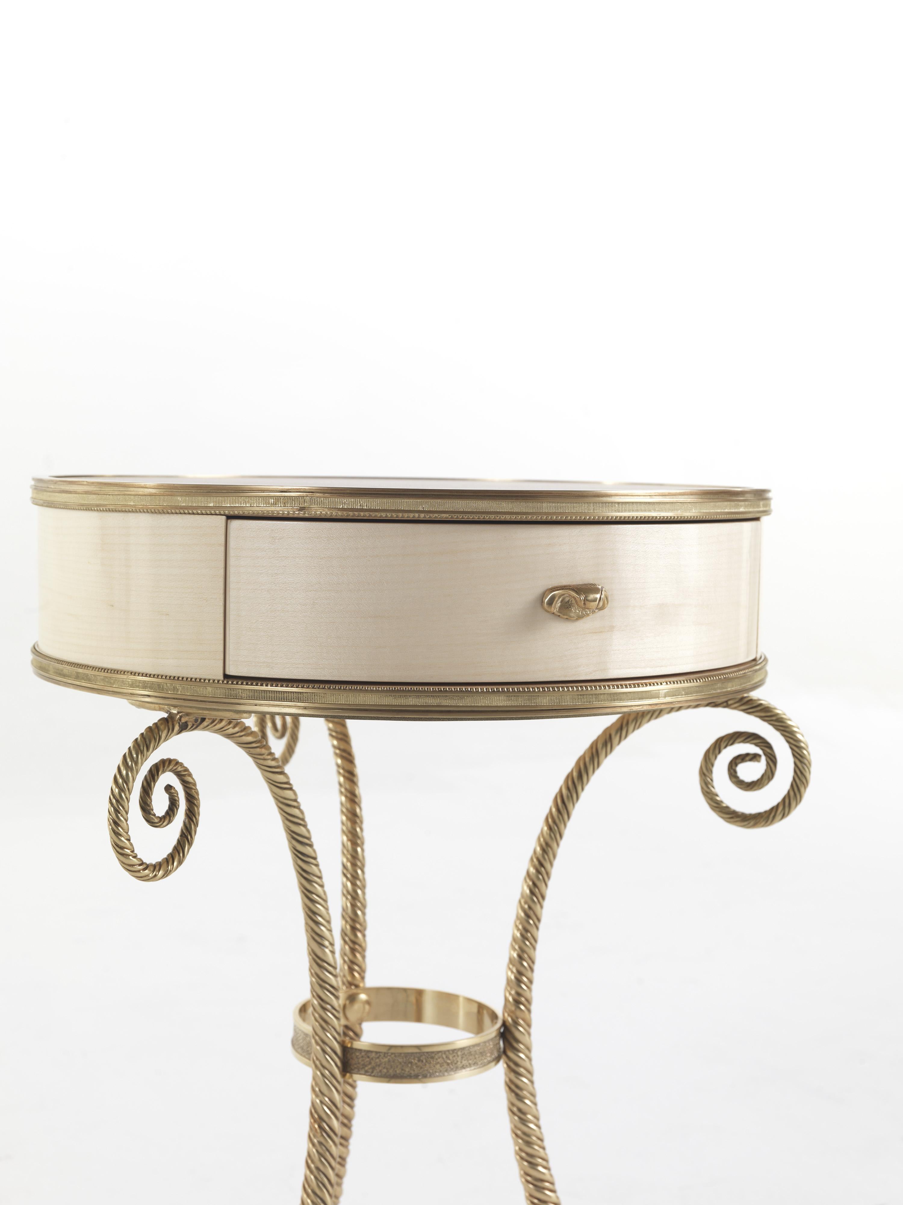 Elegant et gracieux, Torchon est une table de nuit de style Louis XIV, avec une base en laiton, une structure en érable et un plateau en cuir décoré. Il s'agit d'un support idéal pour les lampes, les livres et les magazines, qui rehausse le décor