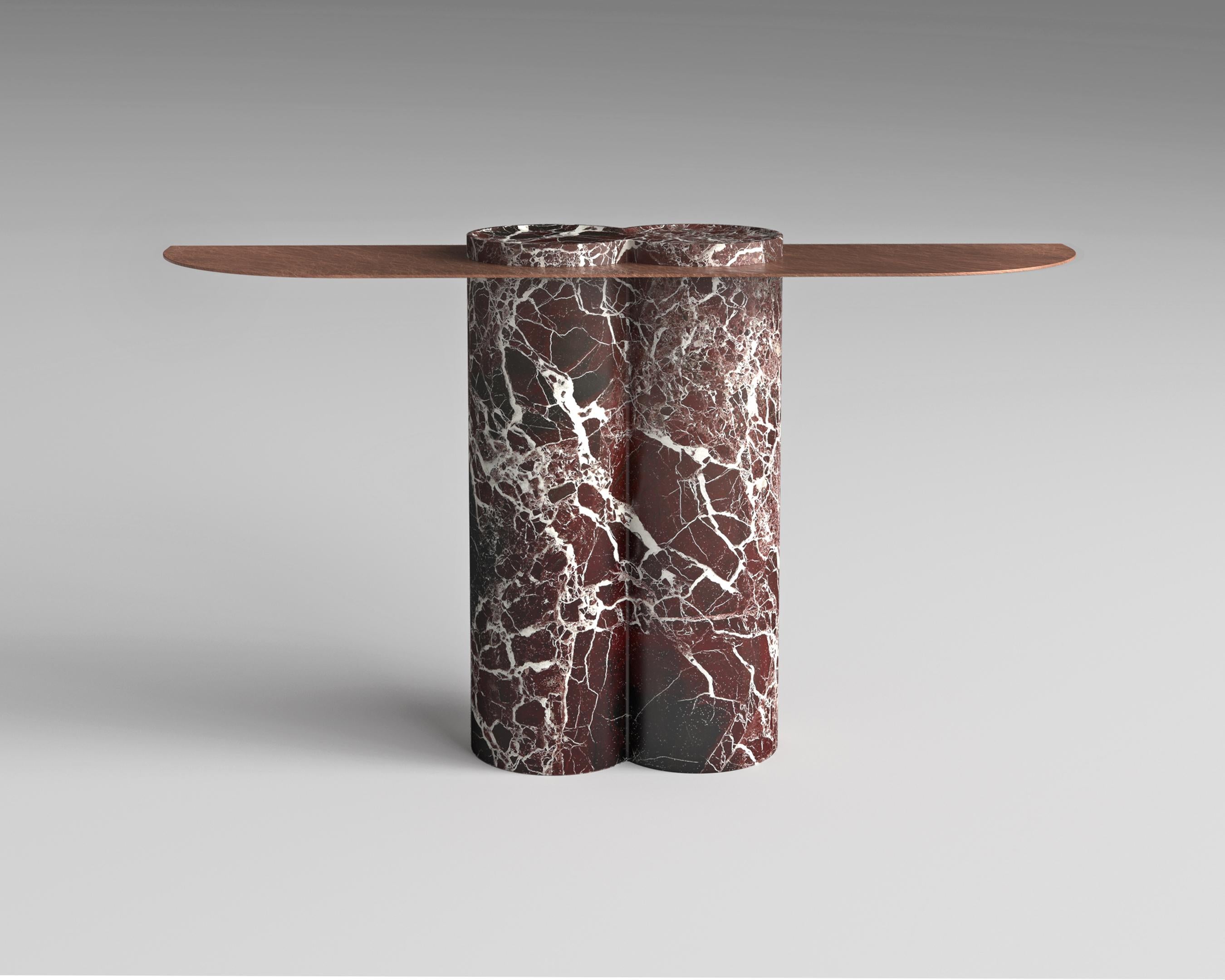Scolpita in un pezzo monolitico di marmo, la base di jumbo Console sostiene un piano in metallo finemente lavorato che conferisce un'ariosa eleganza all'intera composizione. Disponibile in diverse pietre e finiture metalliche, la console Jumbo è
