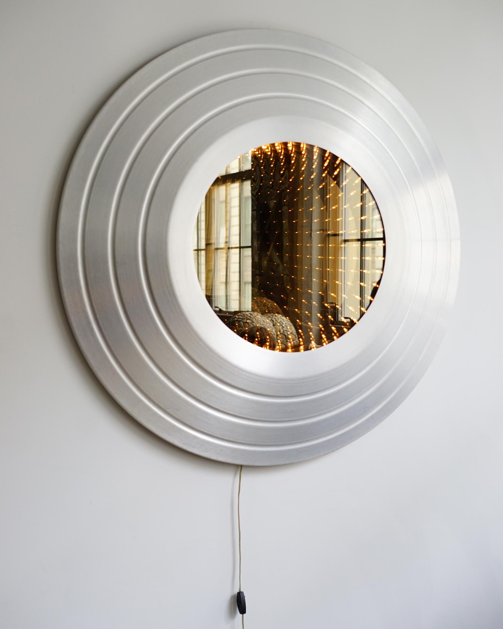 For your consideration is this vintage, all-original infinity mirror. The front glass is a two-way mirror behind which is a single ring of lights which itself is backed by an interior mirror. This creates the illusion of an infinite repetition of a