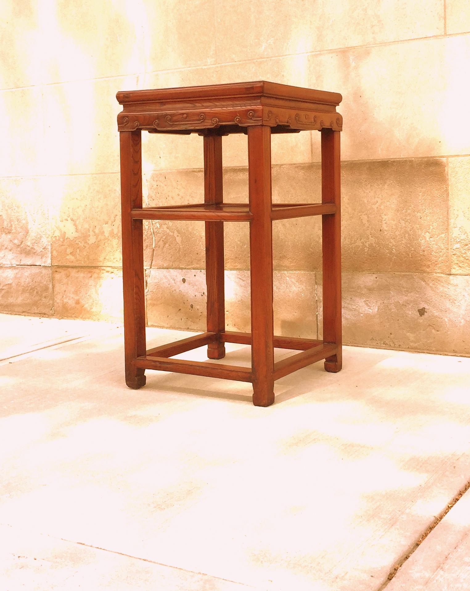 Jumu wood end table with relief carving on apron and shelf and bottom stretchers.
 