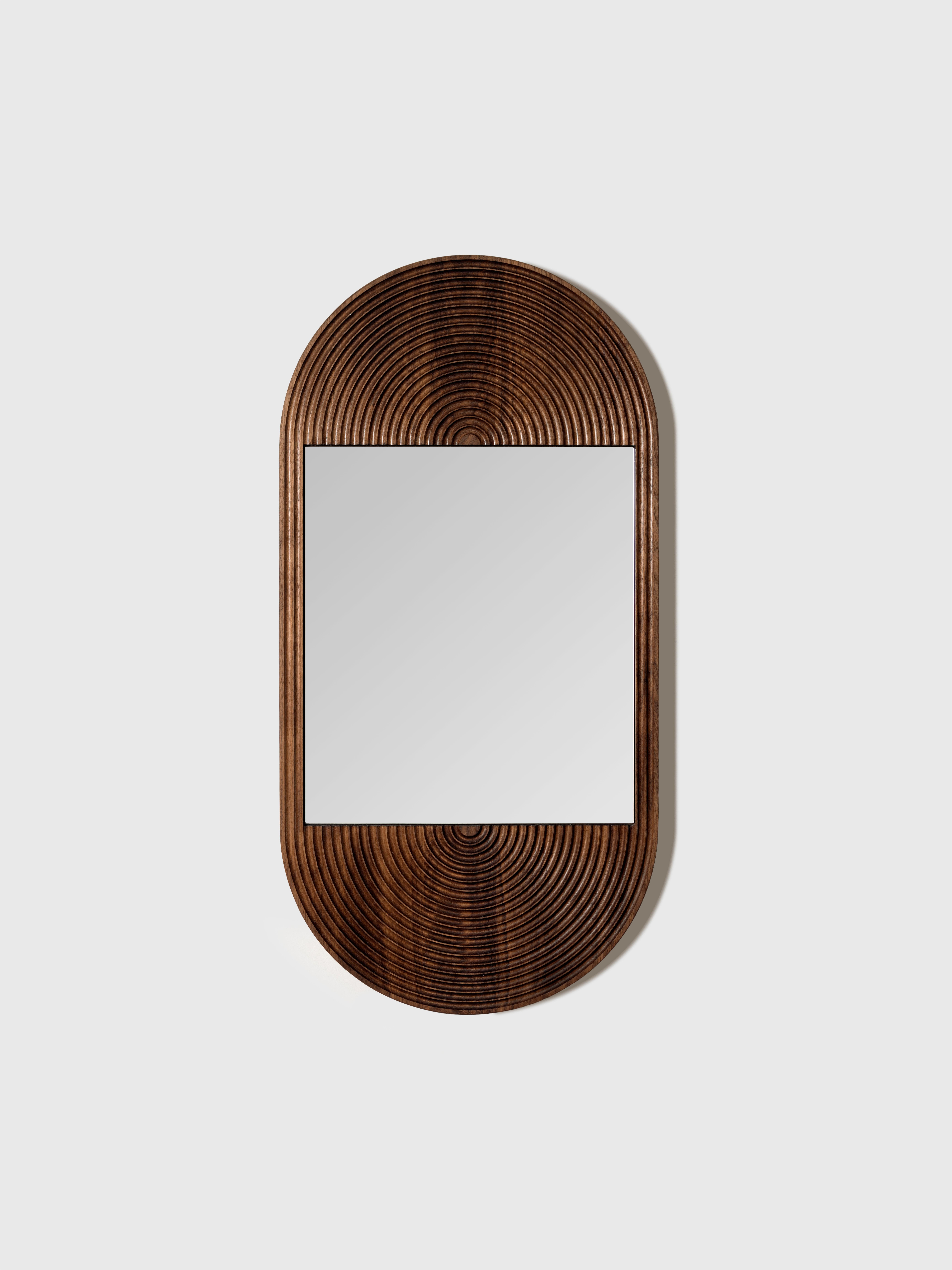 Concentric circles carved into walnut wood creates a stunning sculptural pattern both modern and reminiscent of glamorous 1970s decor. The rounded carving creates beautiful wave-like patterning in the rich walnut grain. This captivating mirror