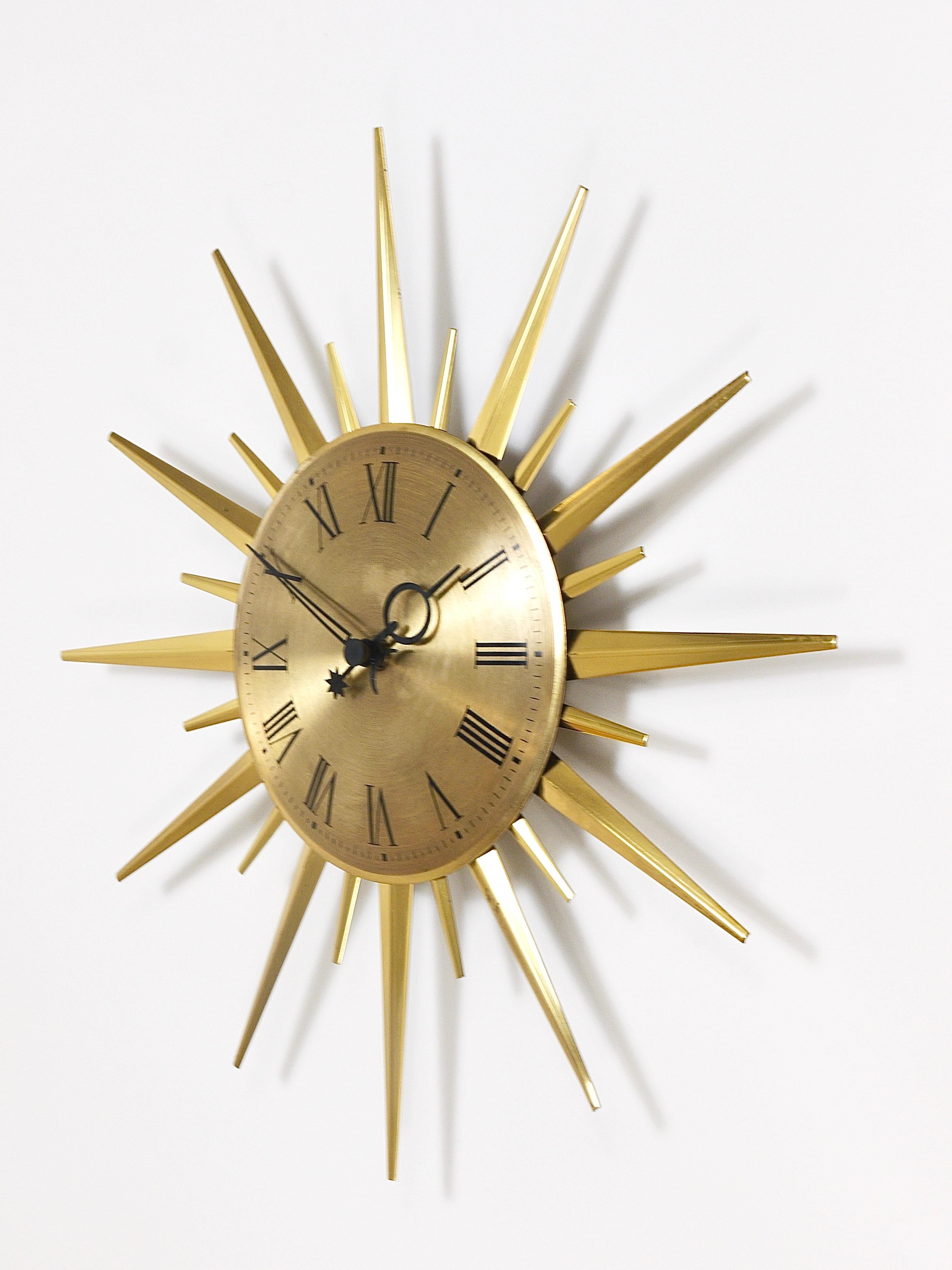 A round Atomic Starburst Hollywood Regency wall clock from the 1960s, executed by Junghans Germany. The clock has a beautiful golden brushed clocks face with nice numbers and hands and its spikes are made of polished brass.This vintage modernist