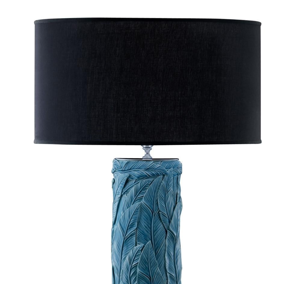 This striking desk lamp, part of the Jungla collection, features an elegant black shade supported by an exquisitely decorated ceramic stand with the vertical juxtaposition of hand-applied leaves with a vivid turquoise hue. The base is in chromed