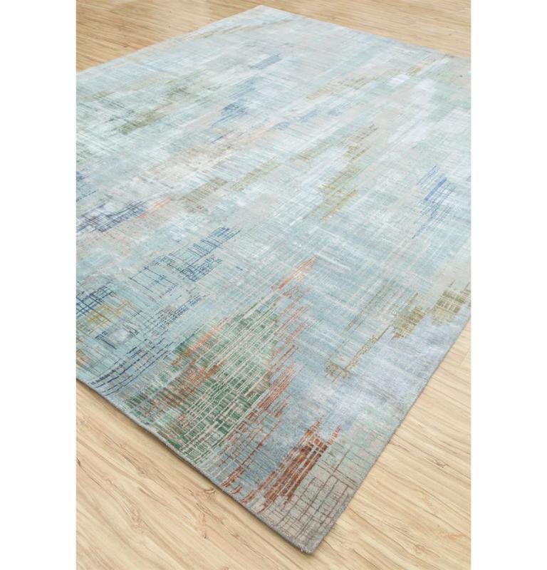 This hand knotted rug from our Unstring By Kavi collection is a testament to exquisite craftsmanship and timeless design. Featuring a captivating pattern in shades of sea mist green and ivory, forming an intricate blend of speed waves that adds a
