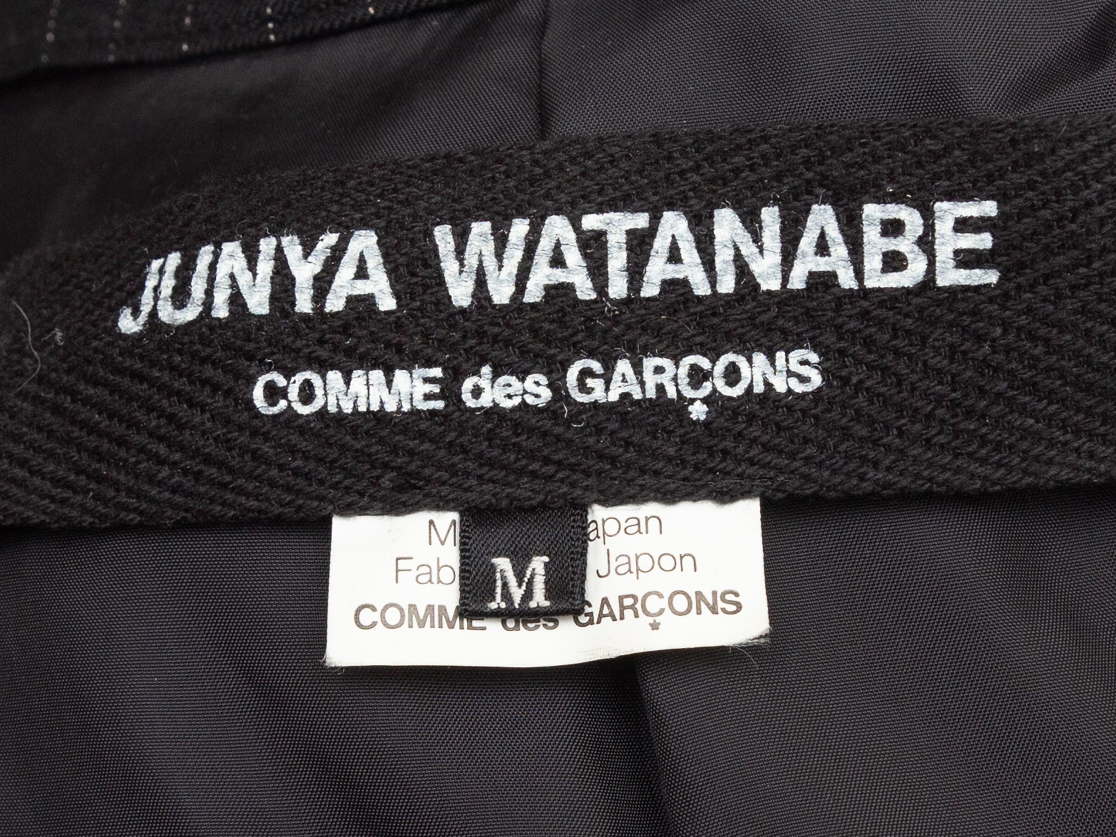 Product details: Black wool pinstripe blazer by Junya Watanabe Comme Des Garcons. Peaked lapel. Dual flap pockets at hips. Single button closure at front. 36