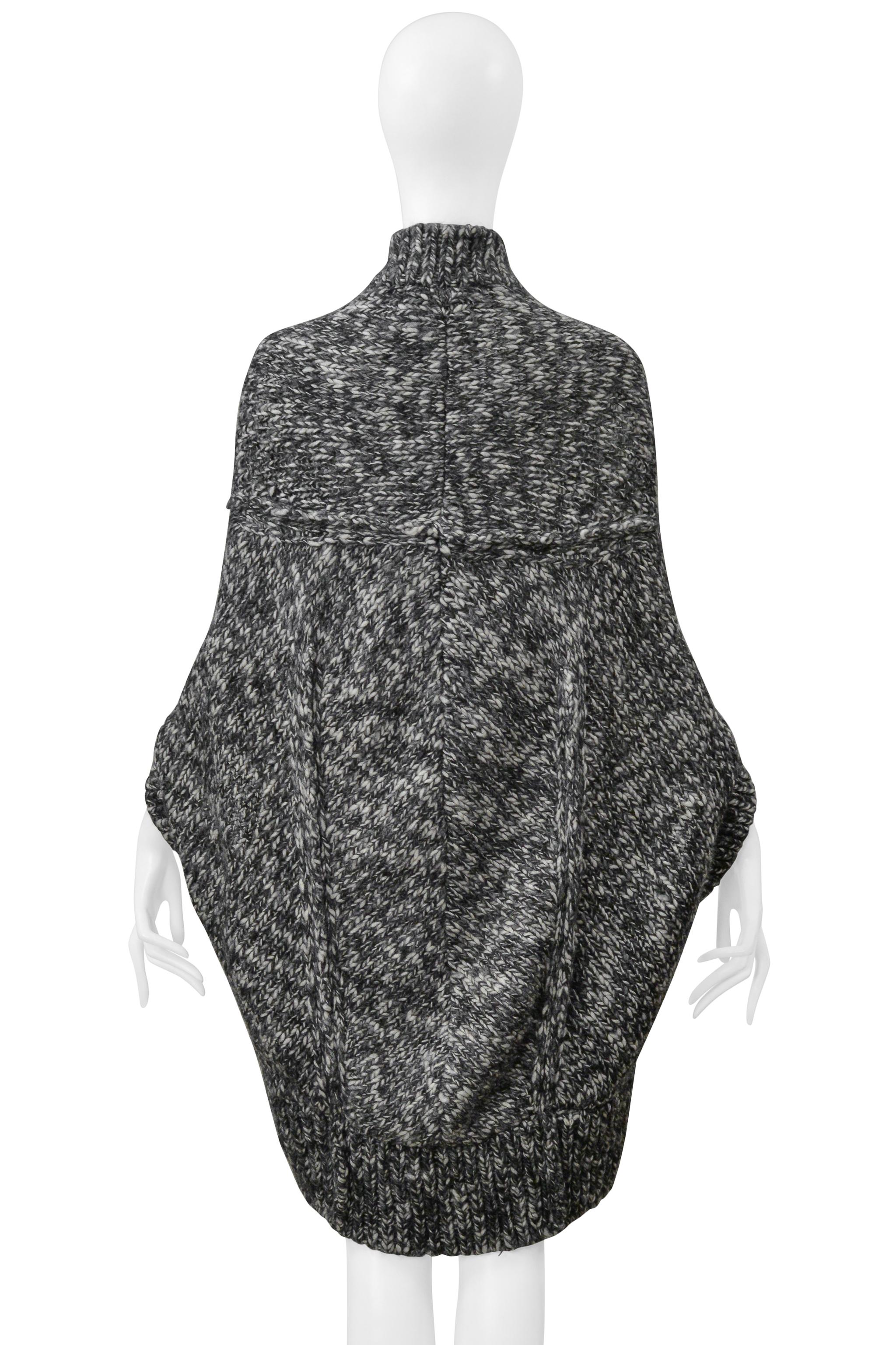 Resurrection Vintage se complace en ofrecer un jersey capa vintage Junya Watanabe de color gris melange de la colección de 2008, con mangas murciélago, grandes botones delanteros, cuello alto, corte holgado y largo por encima de la rodilla.  

Junya
