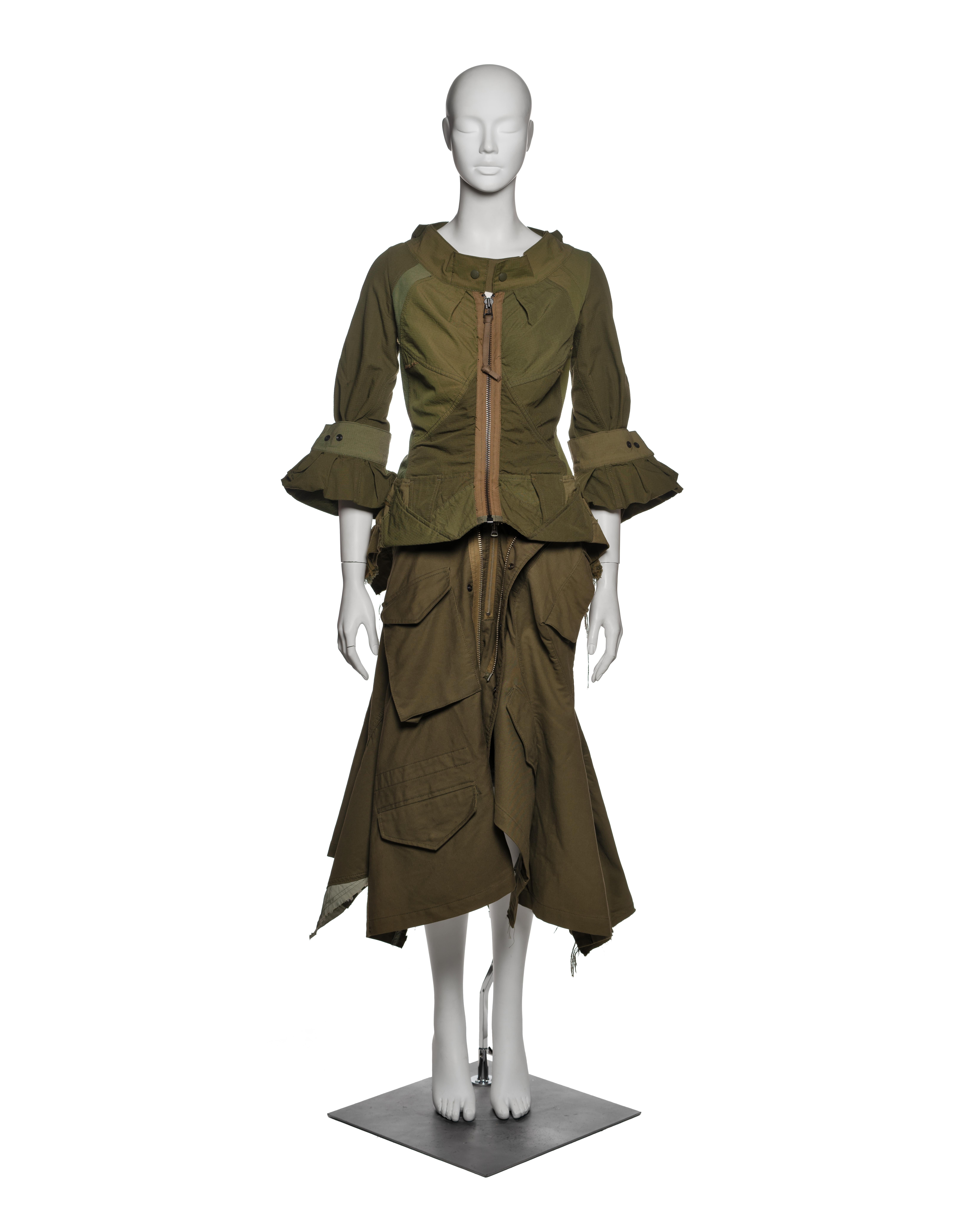 Completo di Junya Watanabe composto da giacca peplo destrutturata e gonna asimmetrica in Ripstop e cotone verde oliva, della collezione Autunno-Inverno 2006. Realizzata principalmente con capi d'abbigliamento militari di recupero, la giacca aderente