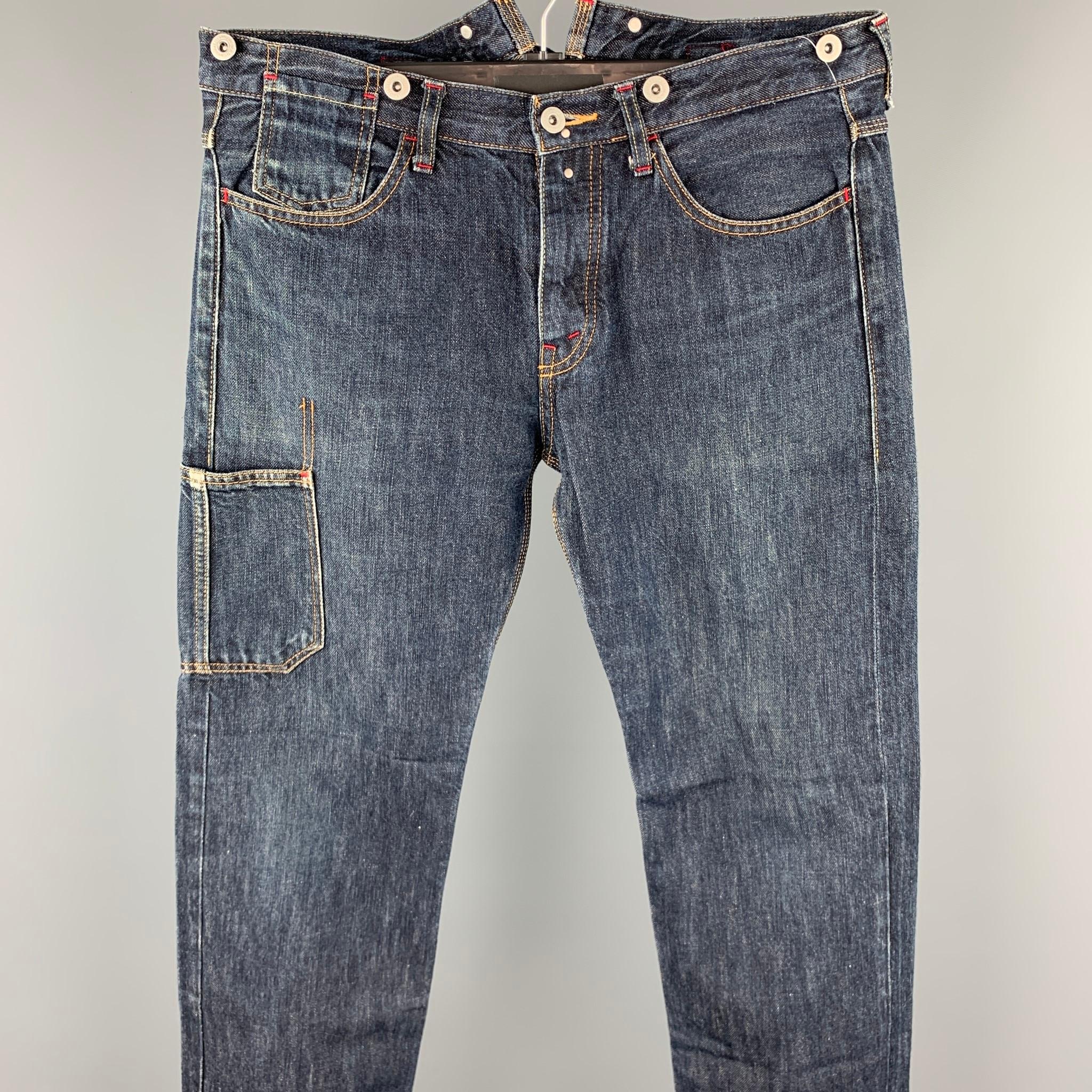 JUNYA WATANABE jeans comes in a indigo denim with contrast stitching featuring a straight leg, front pocket detail, back belt, and a button fly closure. Minor wear. Made in Japan.

Good Pre-Owned Condition.
Marked: L / AD2007

Measurements:

Waist: