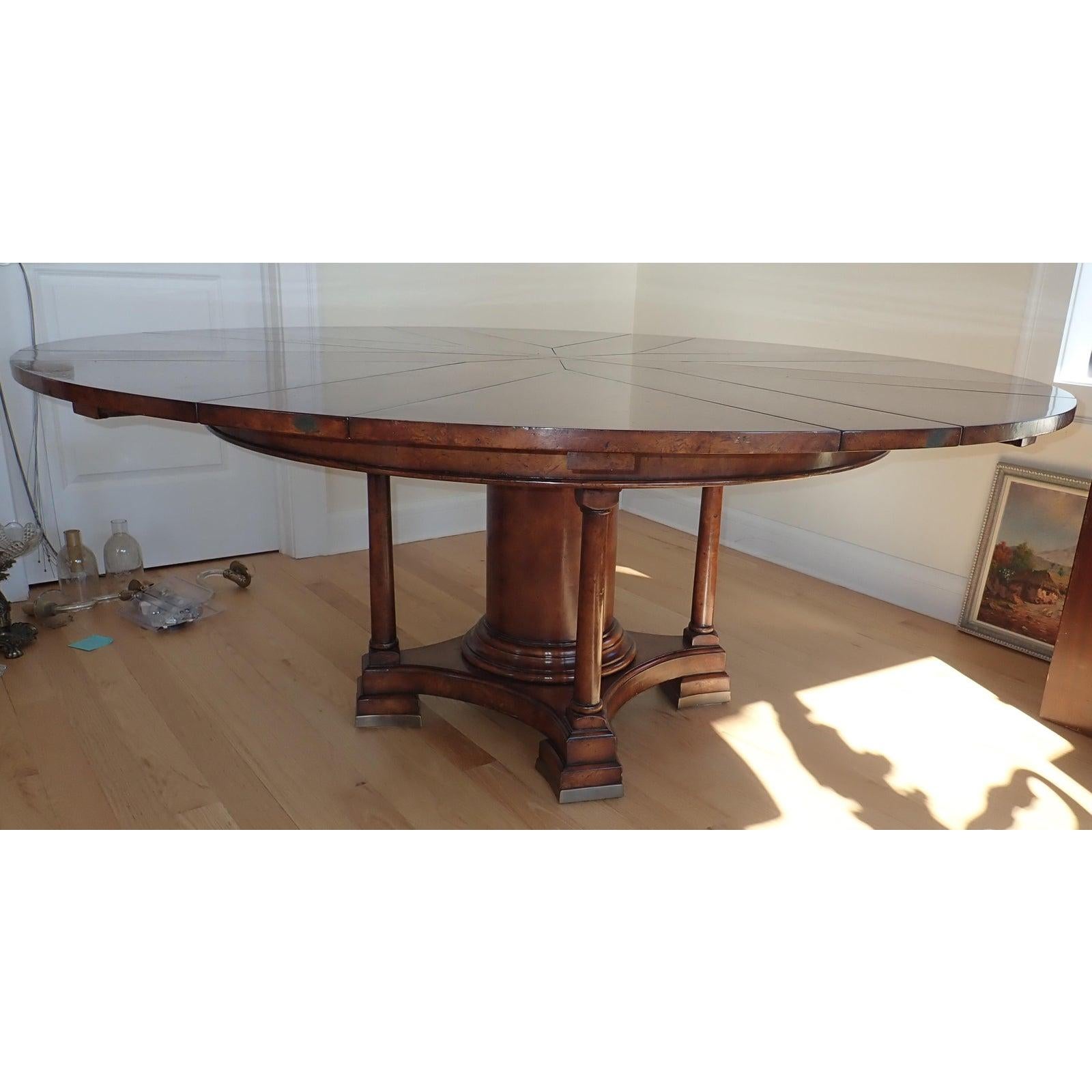Jupe mechanical extension round dining table. Round mechanical burl wood top sits on a large center column surrounded by 4 smaller columns and curved footed base. 8 leaves.

Closed Dimensions 55ʺW × 55ʺD × 30ʺH
Open Diameter 74