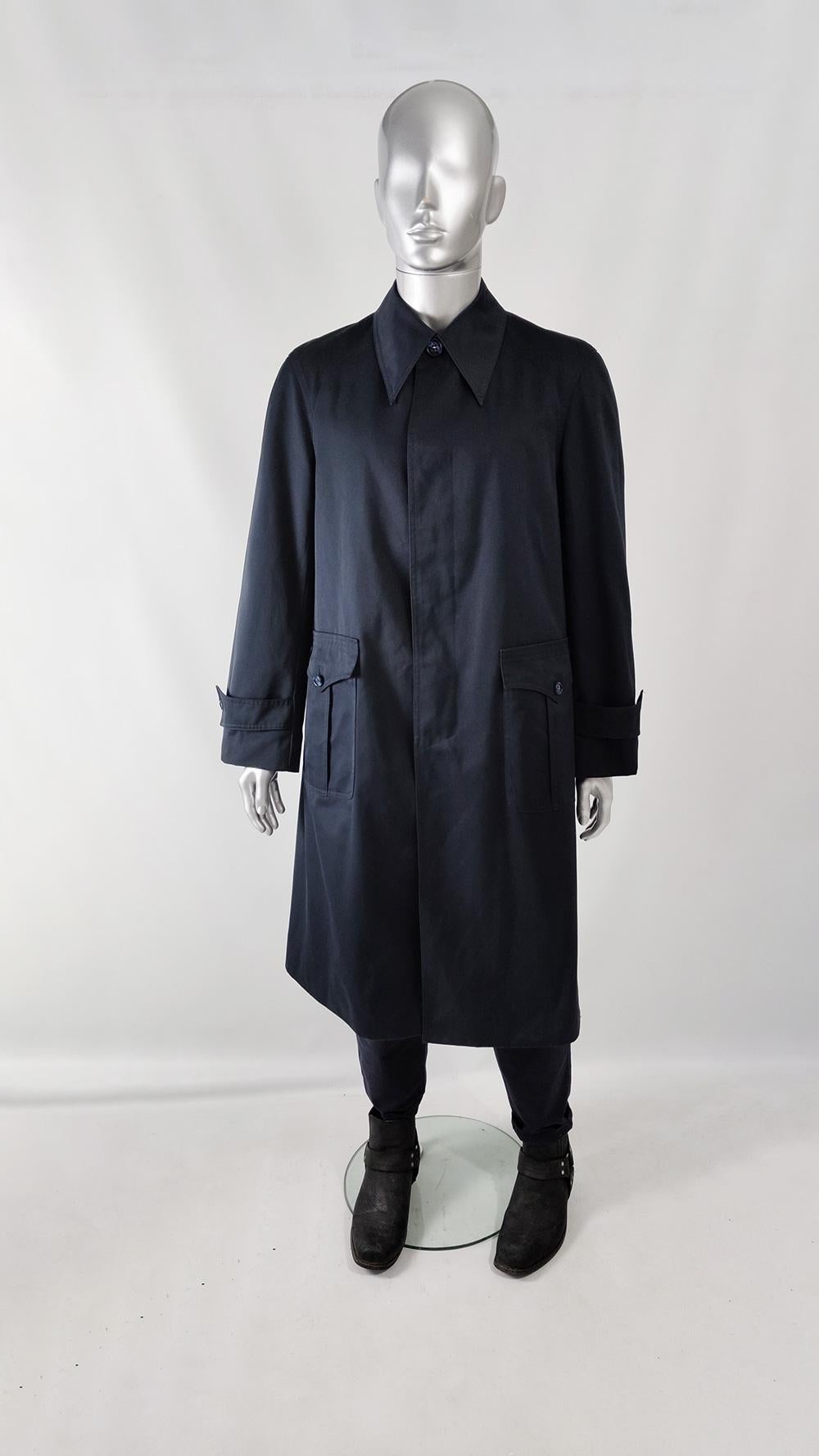 An excellent and rare vintage mens coat from the 70s by luxury French label, Jupiter of Paris. In a navy blue fabric with an extended dagger collar, roomy, oversized fit on the body that flares our from the waist to hem, pleated flap patch pockets
