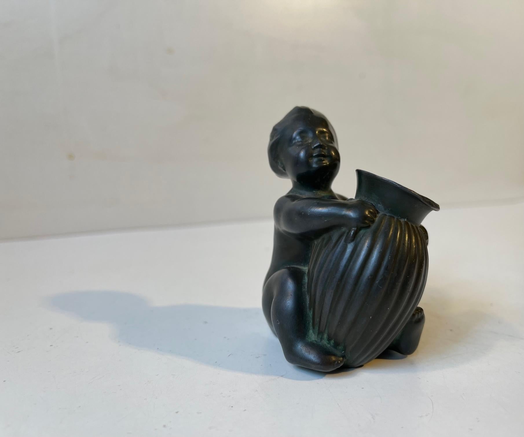 Small figurine/vase/pencil-holder from Just Andersen designed around 1930. Its Composed of Just Andersens own alloy/patina called Disko Metal. The figurine is signed to the side: Just, Denmark, D2096. Measurements: height: 8 cm, depth: 6 cm, wide: 5
