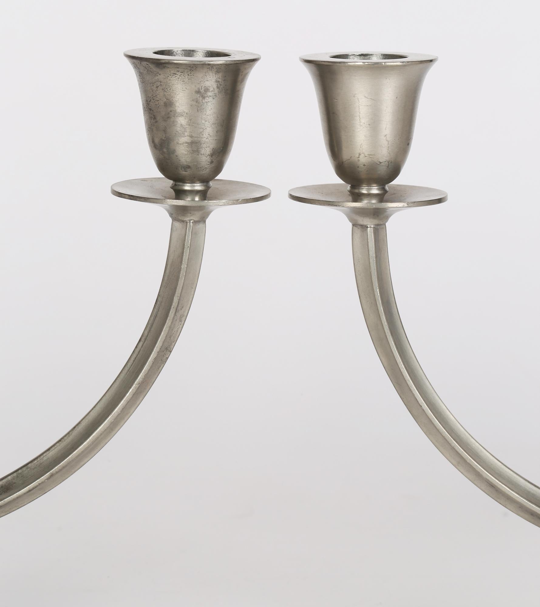 An elegant and stylish pair Danish Art Deco pewter double sconce candlesticks by Just Andersen and dating from around 1930. These candlesticks are typical of Scandinavian design and quality and both stand on an oval pedestal base with a U looped