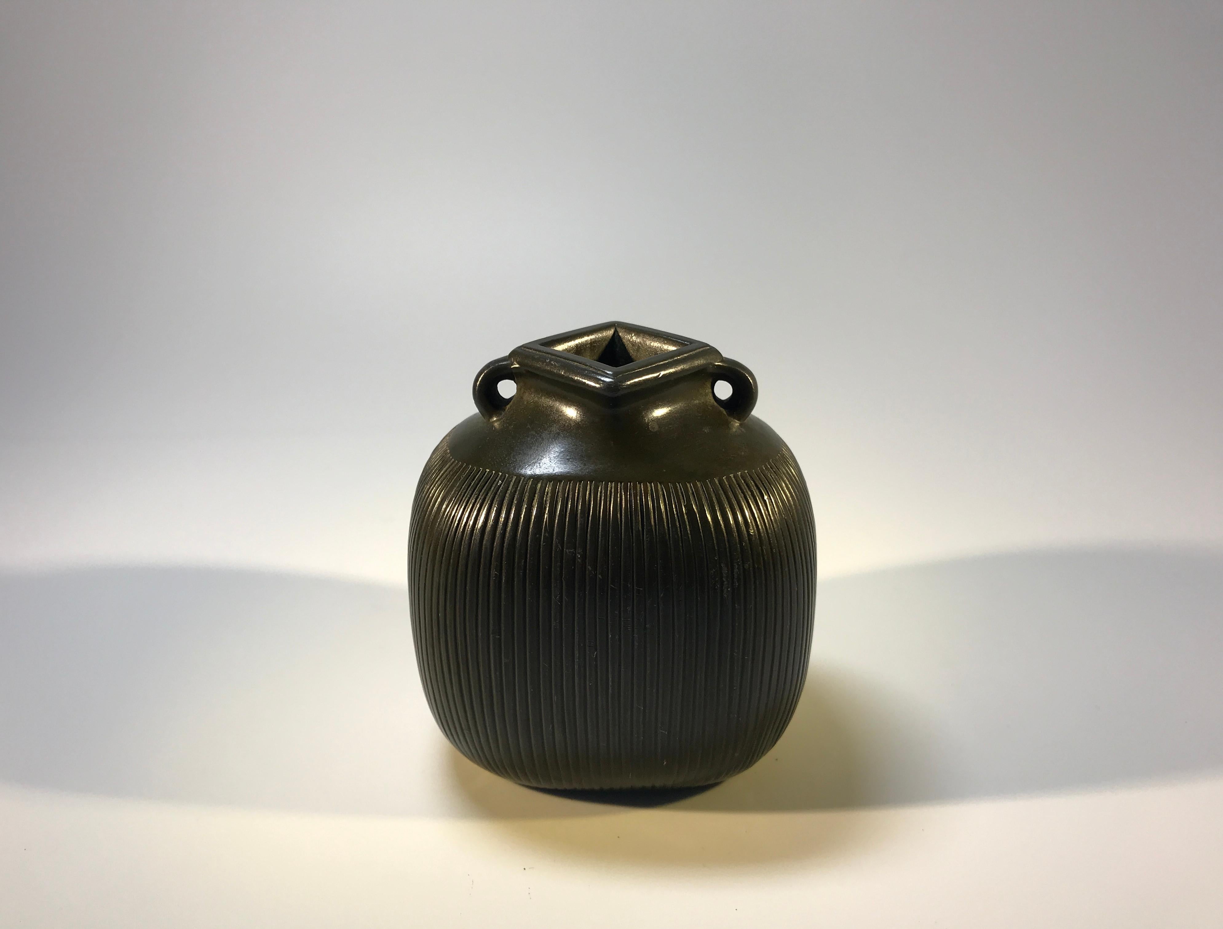 Impressive Just Andersen of Denmark small ribbed vase with an uncommon square neck and twin handles. It has a superb dark patina and is made in Disko metal - a metal specifically invented by Just Andersen by combining lead and antimony
This is a