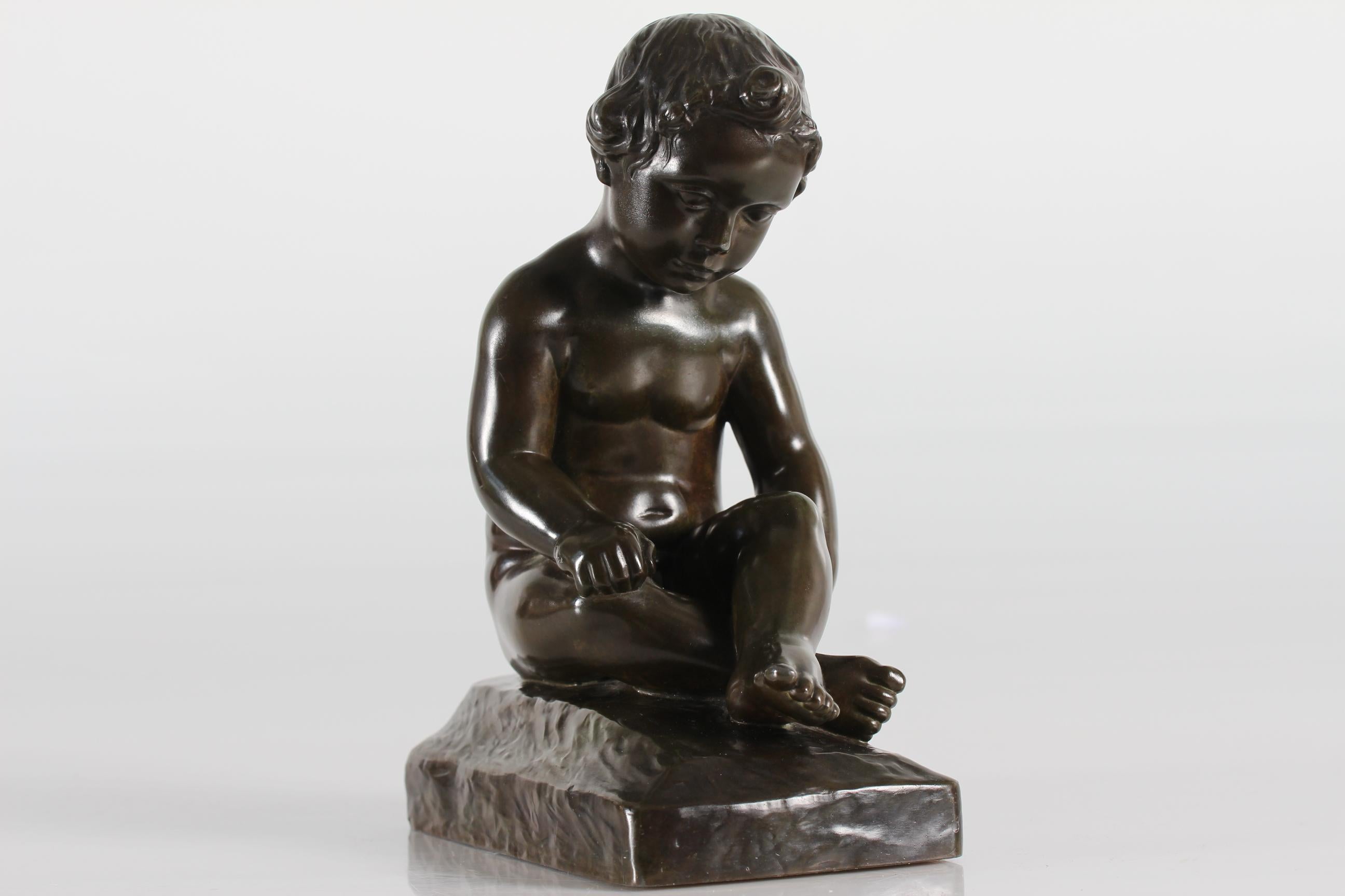 Statuetta originale raffigurante un ragazzo nudo seduto, disegnata da Elna Borch e prodotta dall'artista e scultore danese Just Andersen (1884-1943) 
È stato realizzato in Danimarca negli anni '40 o '50 con il metallo da discoteca creato da Just
