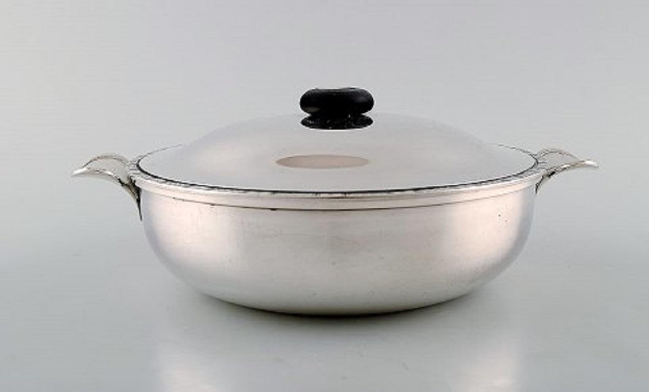 Just Andersen lidded bowl with handles in sterling silver. Edge adorned with chisels and lid knob in ebony. Model number 2309, circa 1950
Stamped.
In very good condition.
Measures: 25.5 x 10.5 cm.
Weight approx. 854 g.