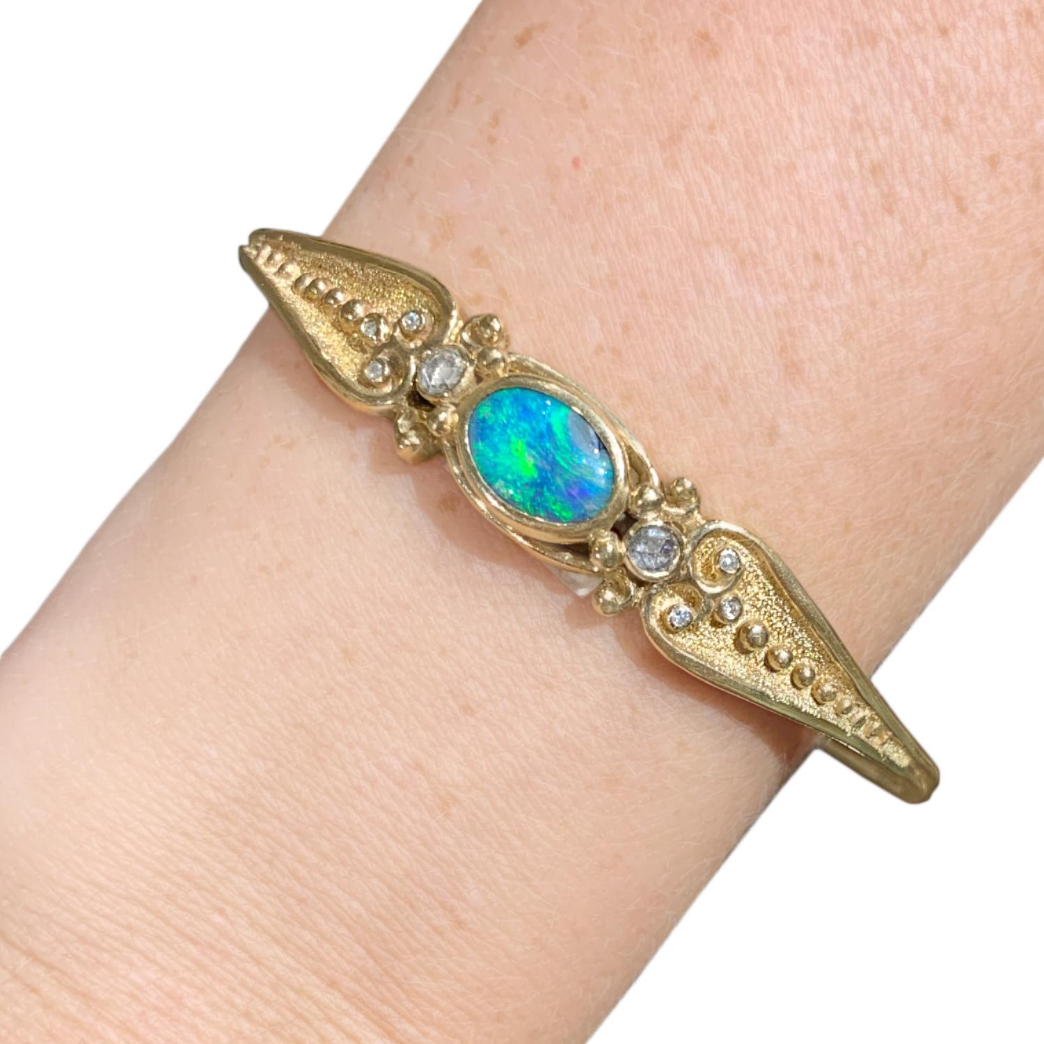 One of a Kind Deco Cuff Bracelet by acclaimed designer Julie Romanenko hand-fabricated in intricately textured and beaded solid 14k yellow gold showcasing a gorgeous 3.0 carat oval black opal cabochon flanked by two rose-cut white diamonds and