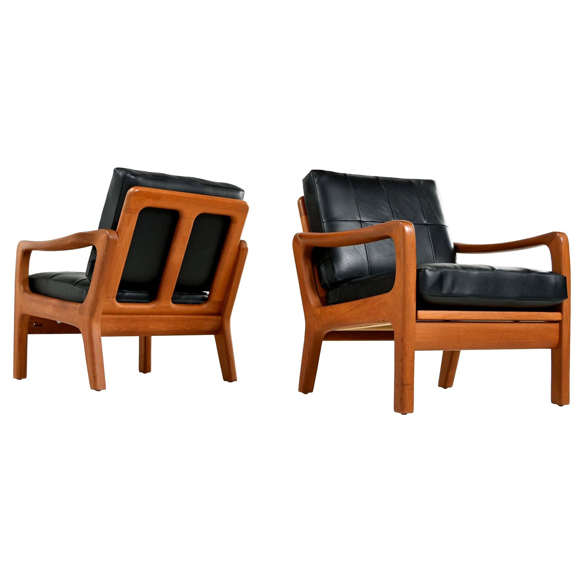 Pair of stunning Juul Kristensen Danish teak lounge chairs with solid teak frames. Fully restored with rock solid rigid construction. The broad, sculpted arms stand out within the sleek, Minimalist, modern, low profile design. Brand new black