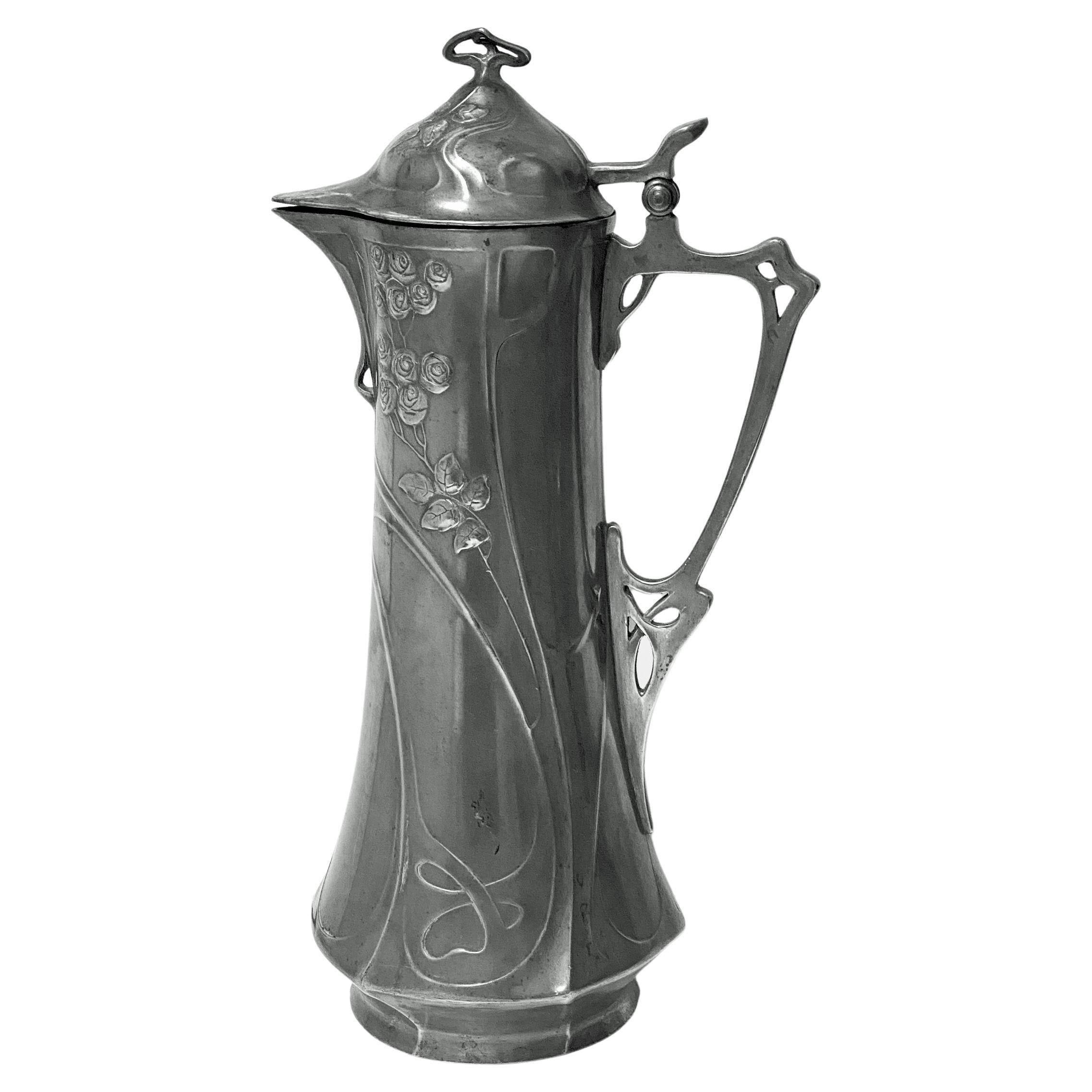Juventa Art Nouveau Jugendstil Pewter Claret Wine Jug C.1900. Large tapering wasted body decorated with stylised roses and foliate relief, with hinged lid and stylised handle stamped Juventa to base. Height: 13.00 inches. Width:7inches. Condition: