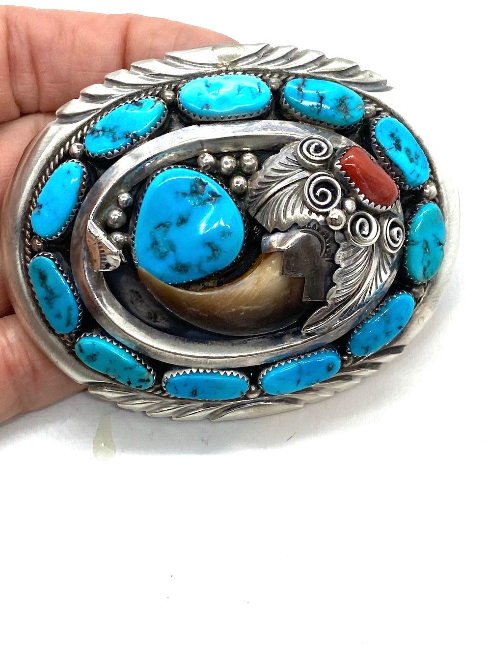 Handmade and intricately designed belt buckle features a large bear claw. The surrounding gemstones are turquoise and coral set in textured bezels.
Color of stones are rich and deep toned.
Bear claw is 2 inches long by 1-3/4 inch wide

Top of Buckle