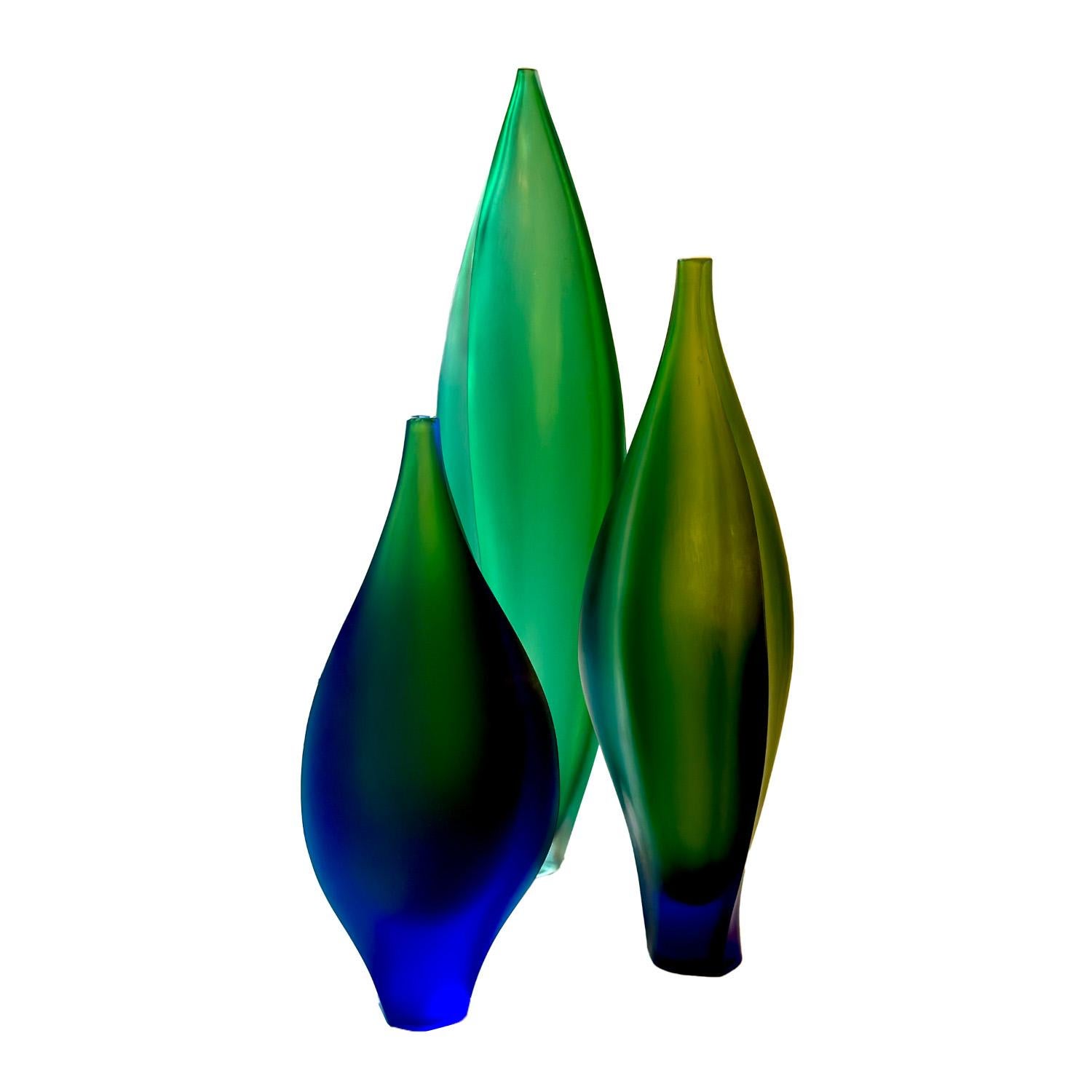 A trio of  blown sommerso glass vessels with a frosted finish by Australian glass makers Kathy Elliot and Benjamin Edols. Each piece of the set is a variation of the organic pod shape crafted in richly colored cobalt blue and green glass. Each