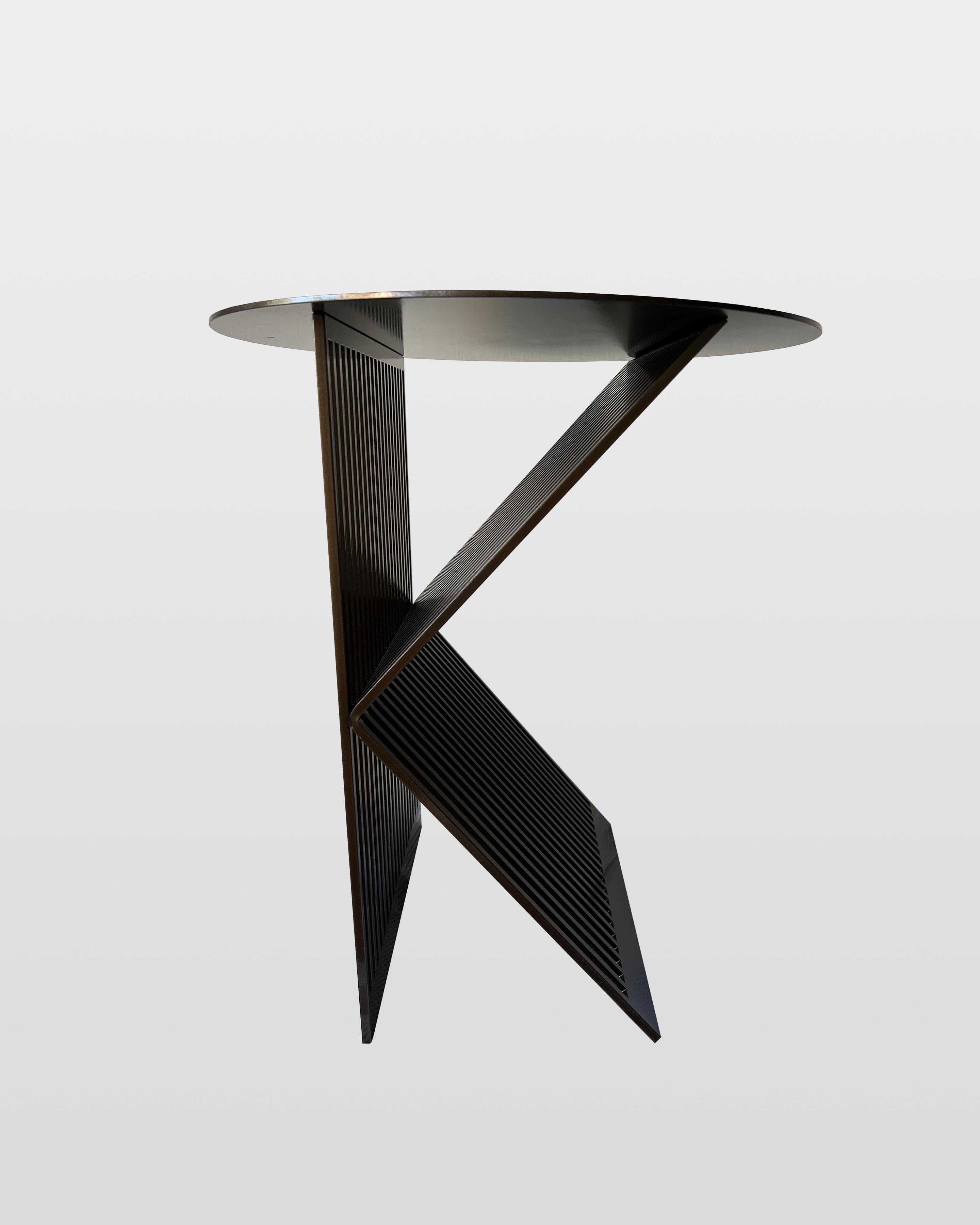 Les lignes contemporaines des tables K.K s'inspirent directement d'une passion personnelle pour l'architecture. Incorporant un rythme entre le solide et le vide, la continuation des tiges d'acier prolonge une voix silencieuse entre la lumière et