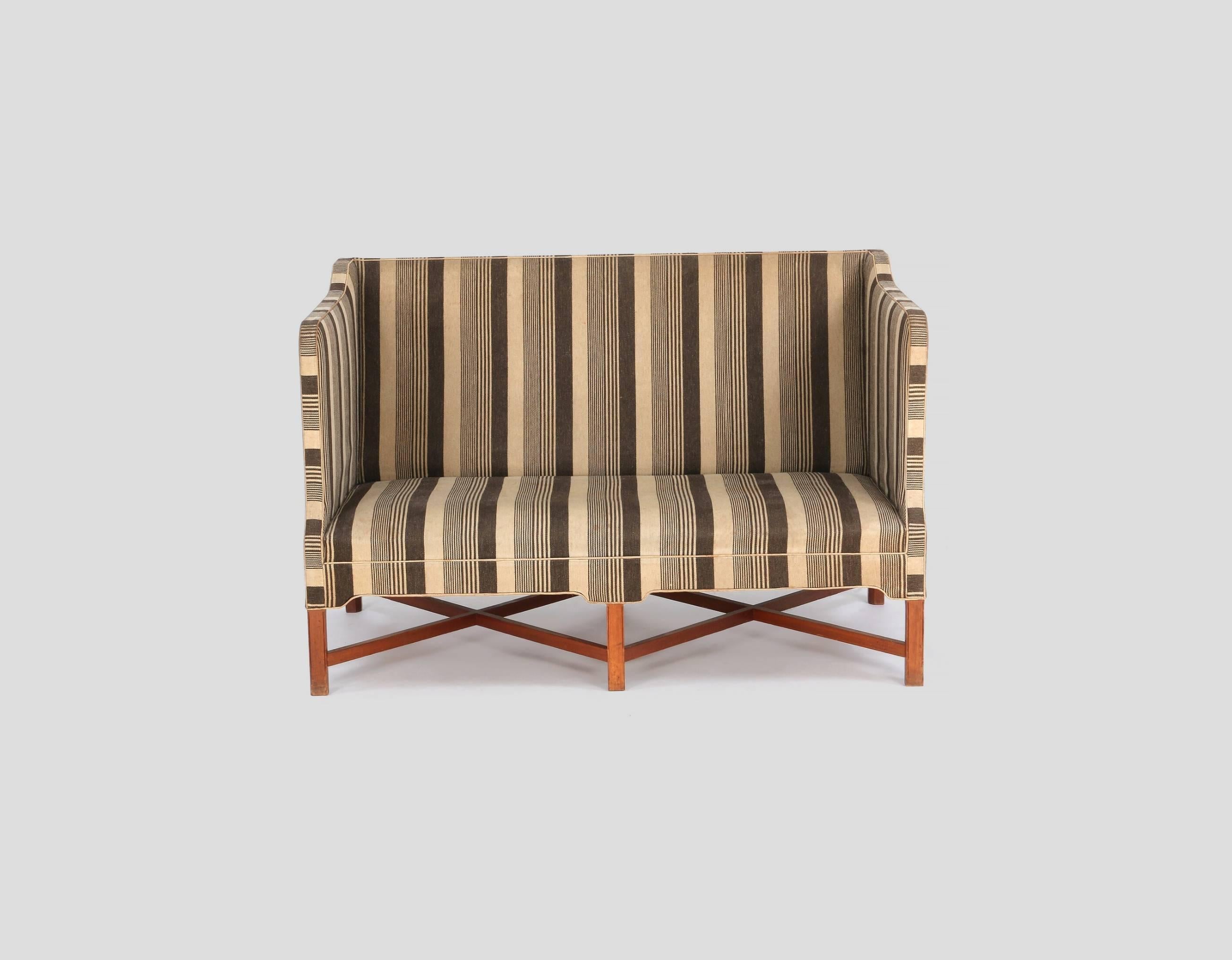 Rare Kaare Klint Model 4118 two-seat box sofa with profiled cross legged mahogany frame. Made by Rud Rasmussen, Copenhagen, Denmark. The fabric has some stains and minor holes so the sofa is offered with complimentary re-upholstery in customer
