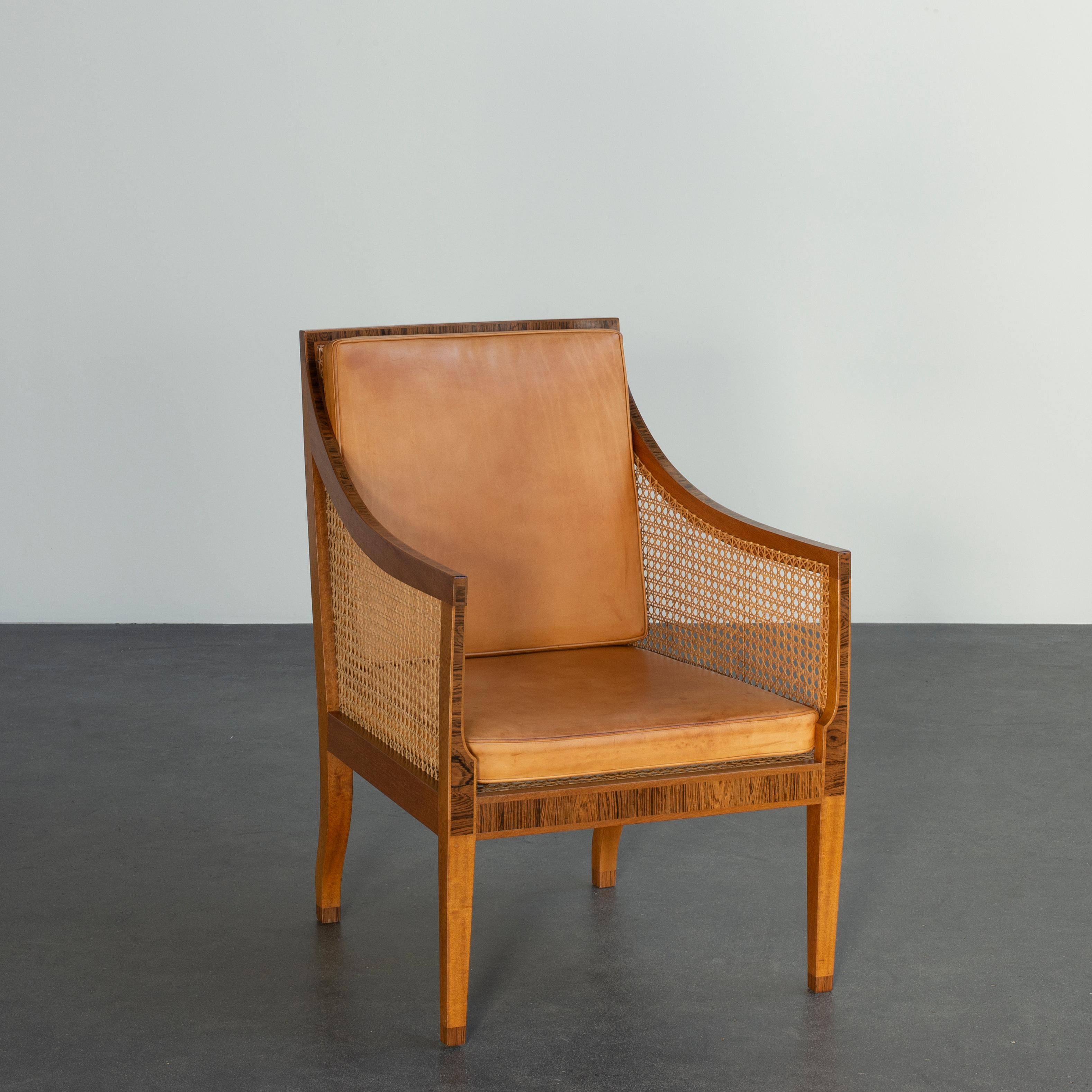 Kaare Klint bergere of mahogany. Sides, seat and back with woven cane. Loose cushions in seat and back upholstered with patinated leather. Executed by Rud. Rasmussen cabinetmakers.