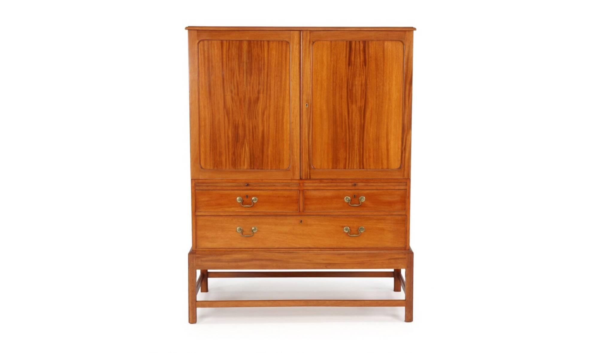 Kaare Klint, Danish midcentury cabinet in mahogany for Rud Rasmussen cabinetmakers, Copenhagen. Cabinet features a pair of doors concealing five pullout shelves over three exposed drawers with brass 'handlebar' pulls.

Signed with decal