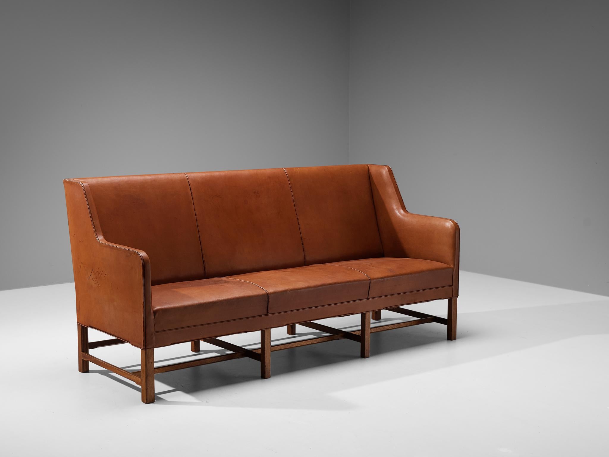 Kaare Klint for Rud Rasmussen, sofa model '5011', leather, wood, Denmark, design 1935.

Classic and elegant Scandinavian three-seat sofa by Kaare Klint designed in 1935. The high back is structured by vertical lines into three parts that flow over